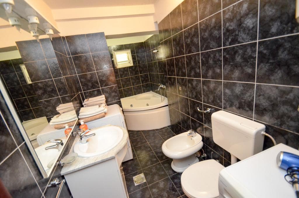 Bathroom with a corner bathtub and dark tiles in a house for sale in Kotor, Montenegro.
