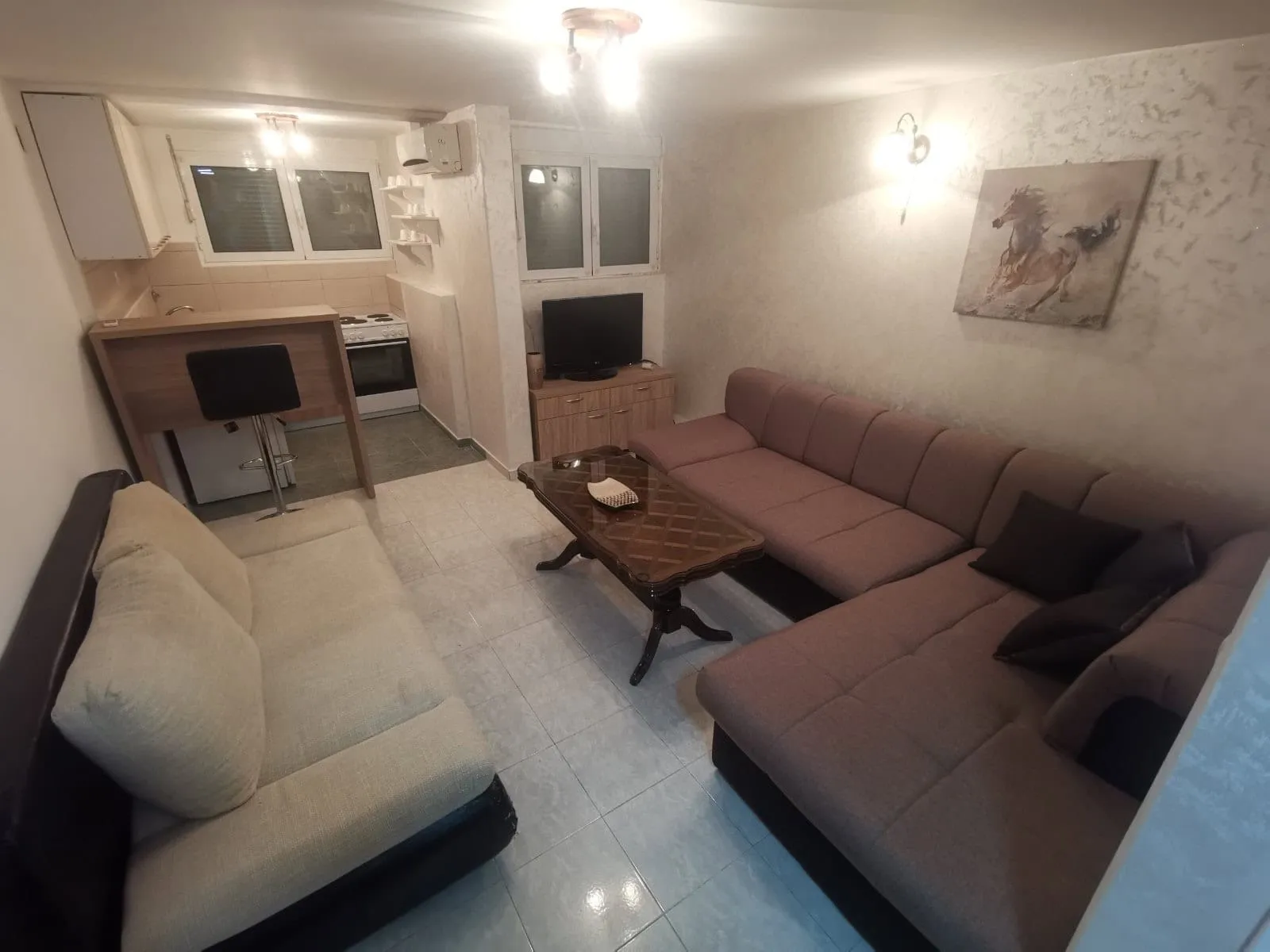 Living room featuring a large sectional sofa, wooden coffee table, and an open kitchen area in the background.