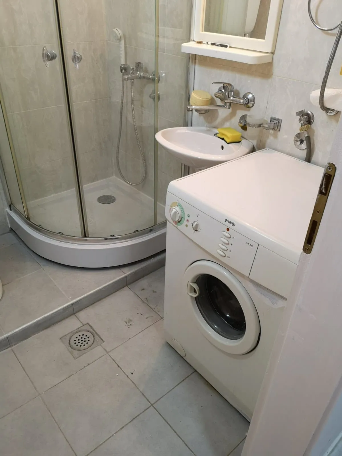 Bathroom featuring a glass shower enclosure, wall-mounted sink, and a white washing machine.