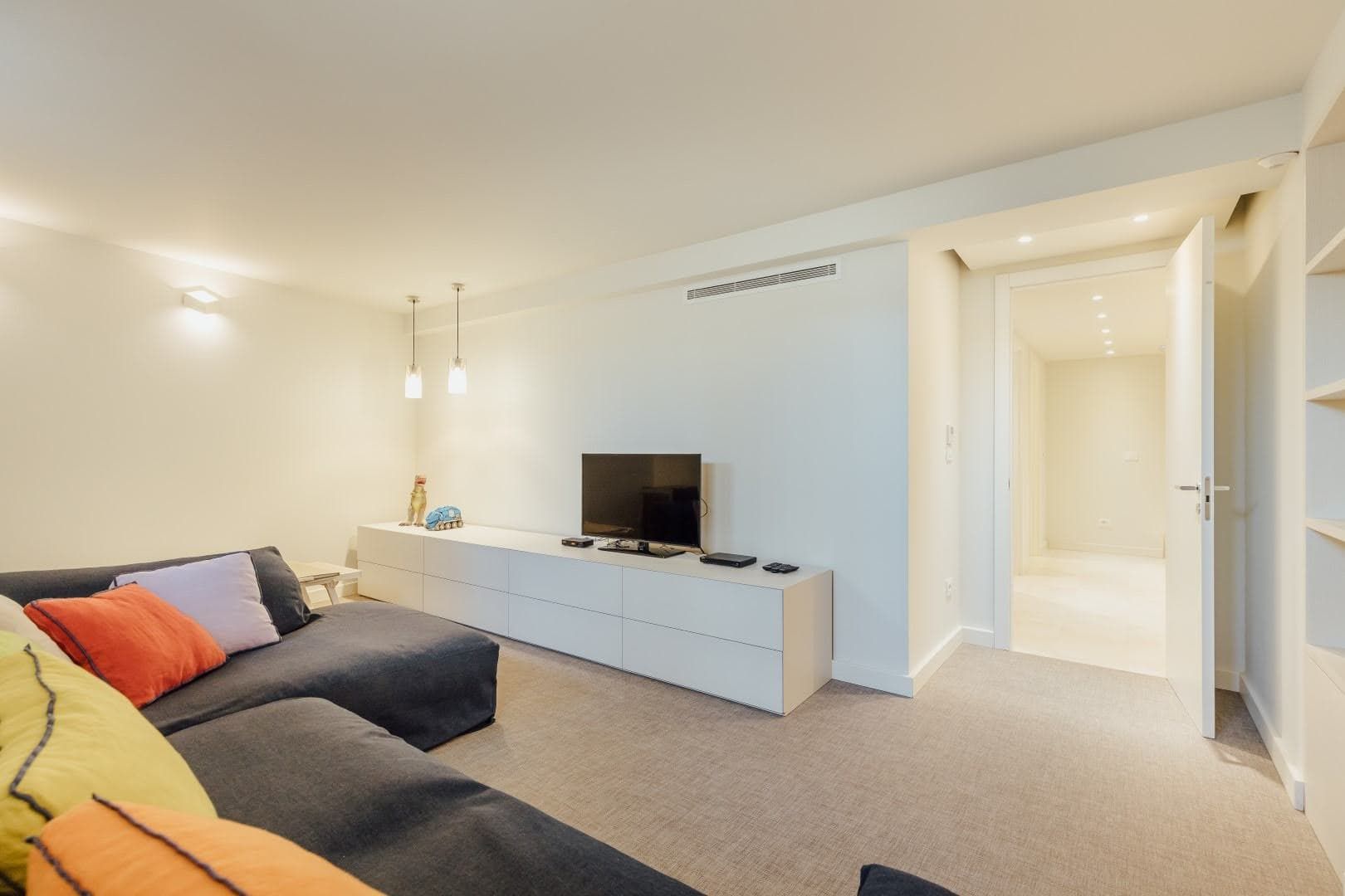 Modern living room with a gray sofa and white furniture in a villa in Pržno, Montenegro. Bright interior with recessed lighting.