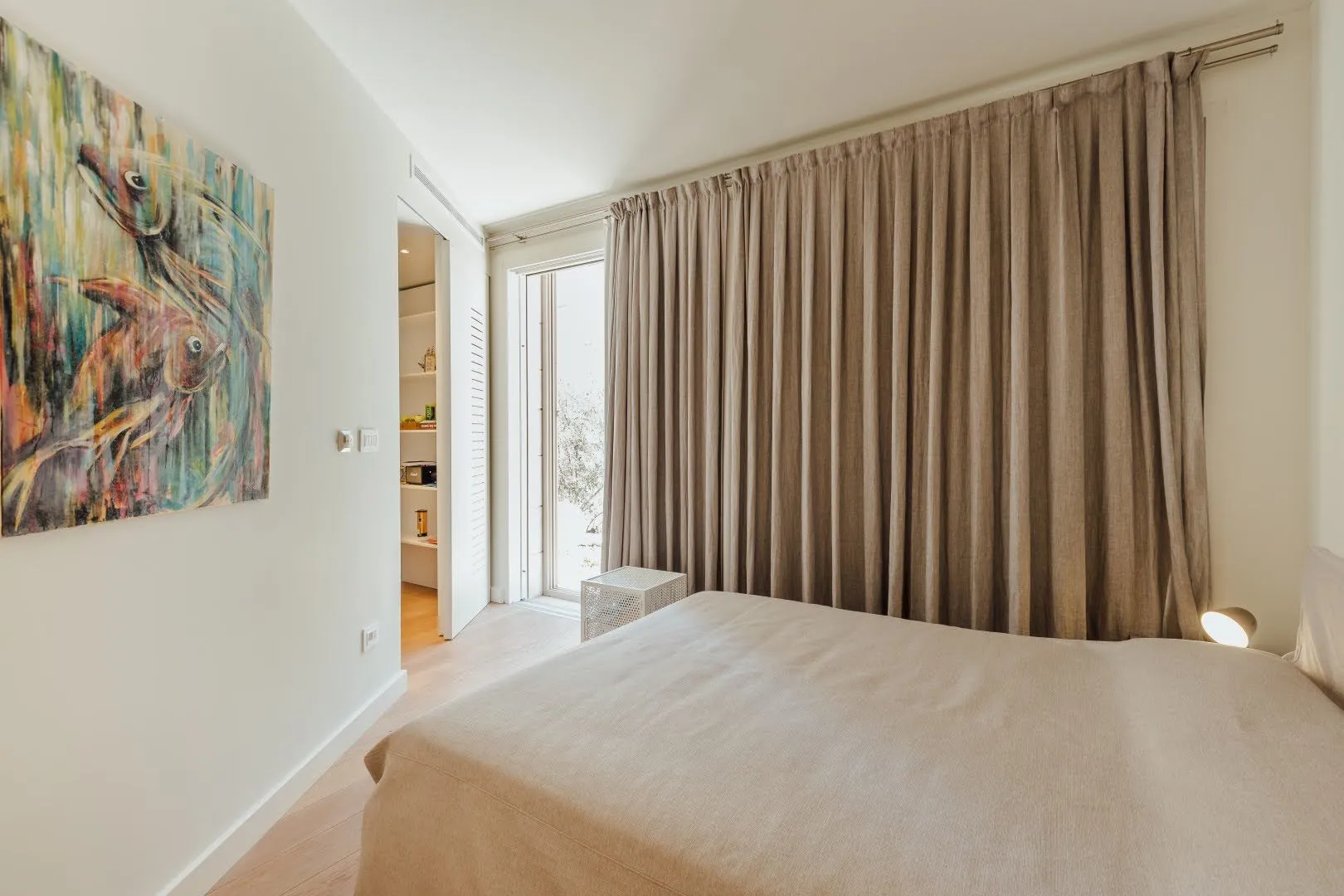 Bedroom featuring a large bed, beige curtains, and a colorful abstract painting on the wall.