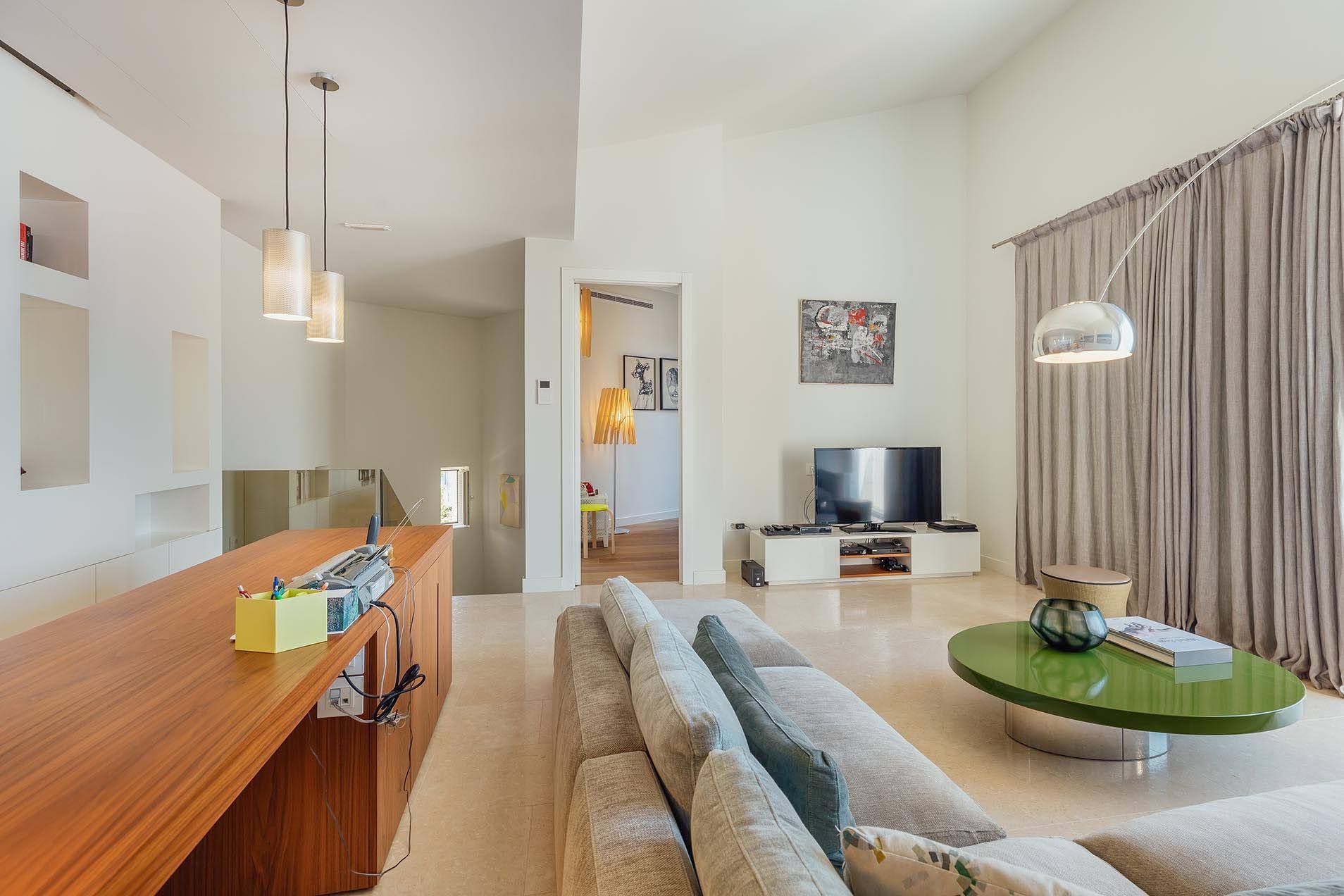 Modern living room with high ceilings in a villa in Pržno, Montenegro: gray sofa, green table, and stylish decor.