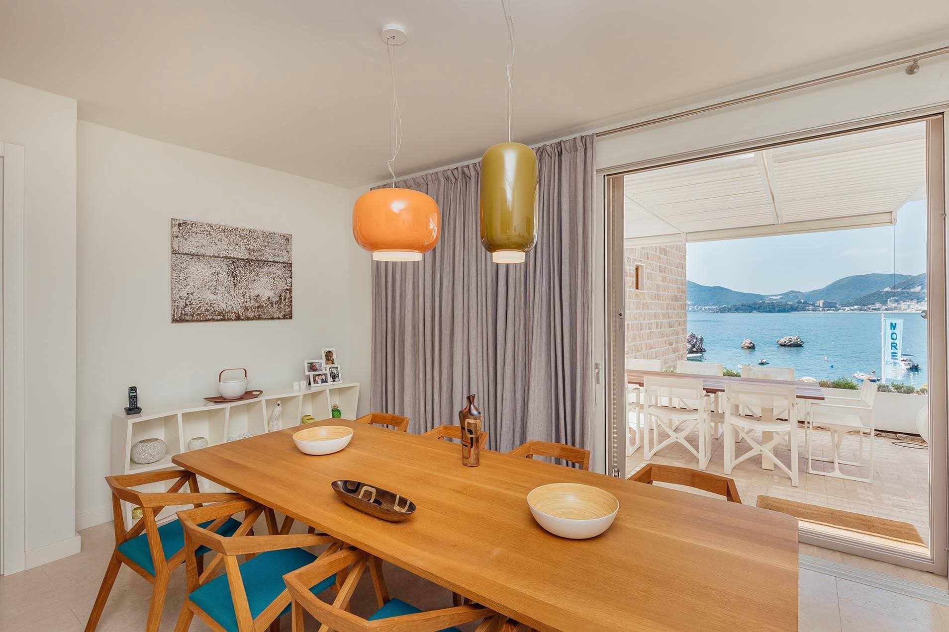 Dining area in a villa in Pržno, Montenegro: wooden table, sea view from the terrace, and modern interior.