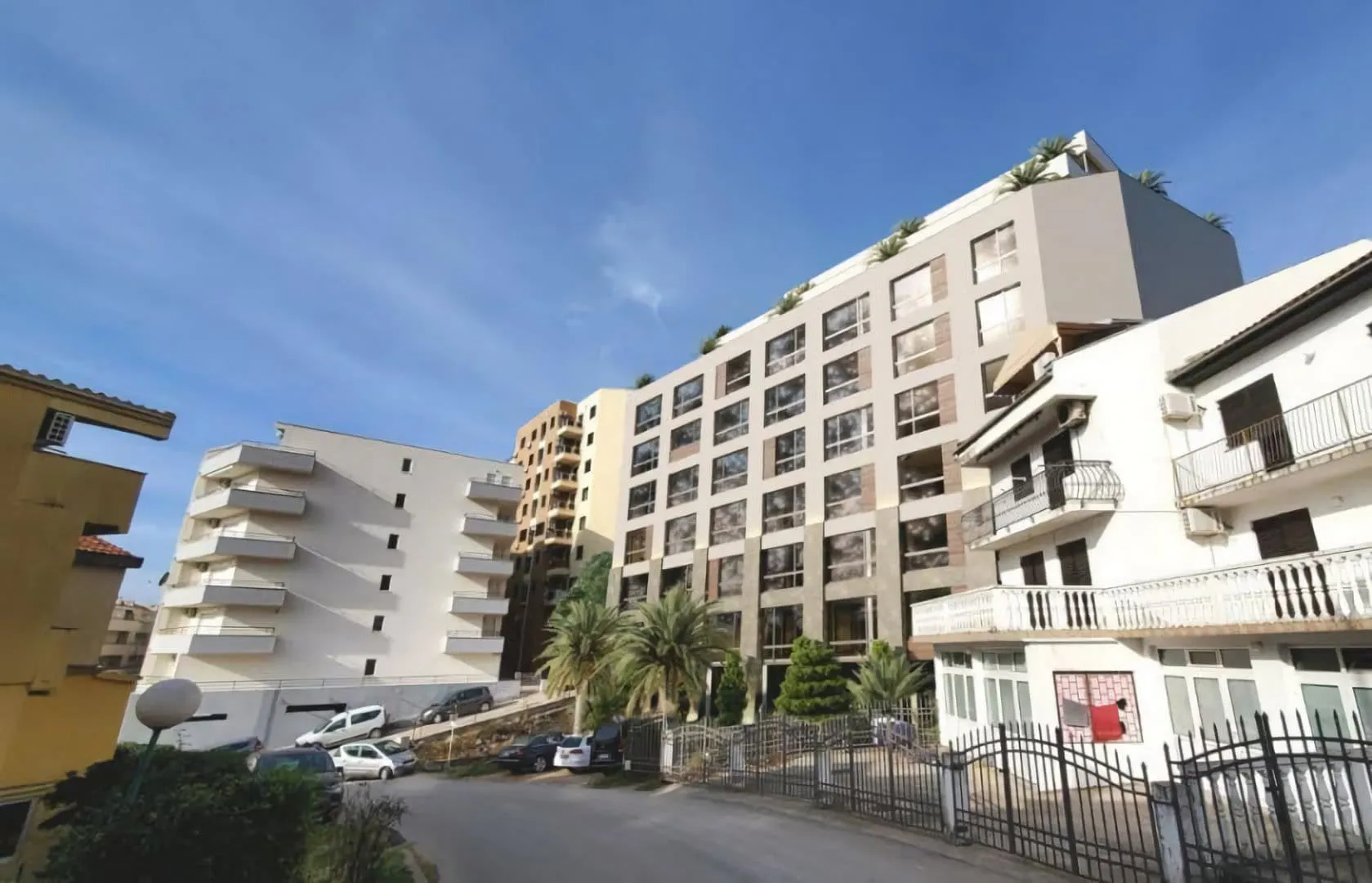 Exterior view of multi-story residential buildings with balconies under a blue sky.