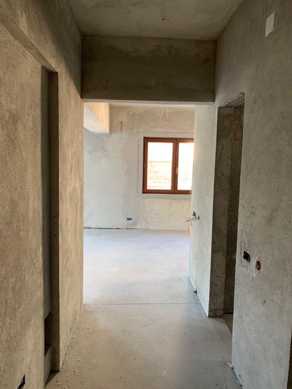 Living room in rough finishing stage in a villa in Dobrota, Montenegro: concrete walls and a view from the window.