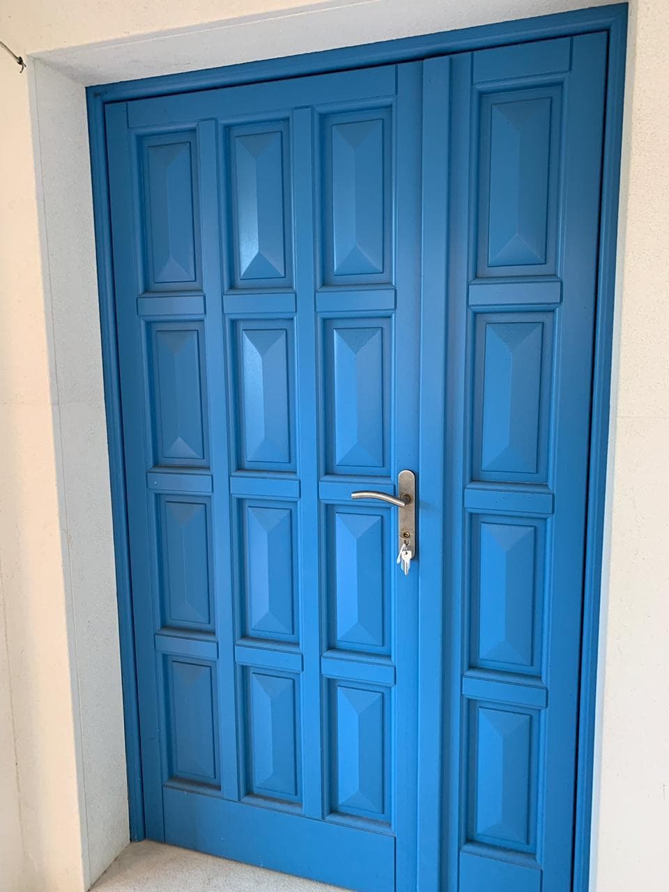 Blue paneled villa entrance door in Dobrota, Montenegro. High-quality house facade finish.