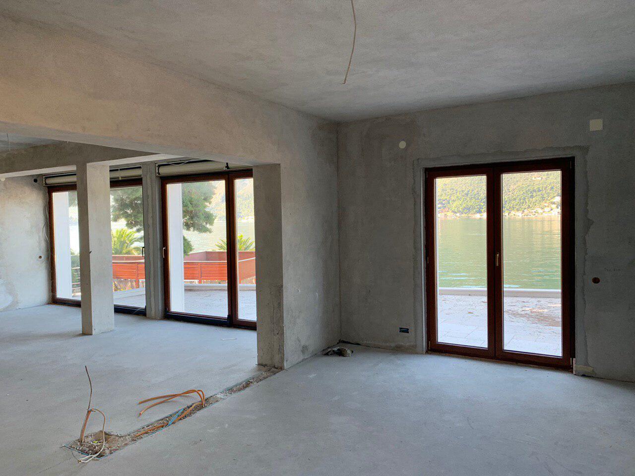 Unfinished living room in a villa under construction in Dobrota, Montenegro, with panoramic windows and sea view.
