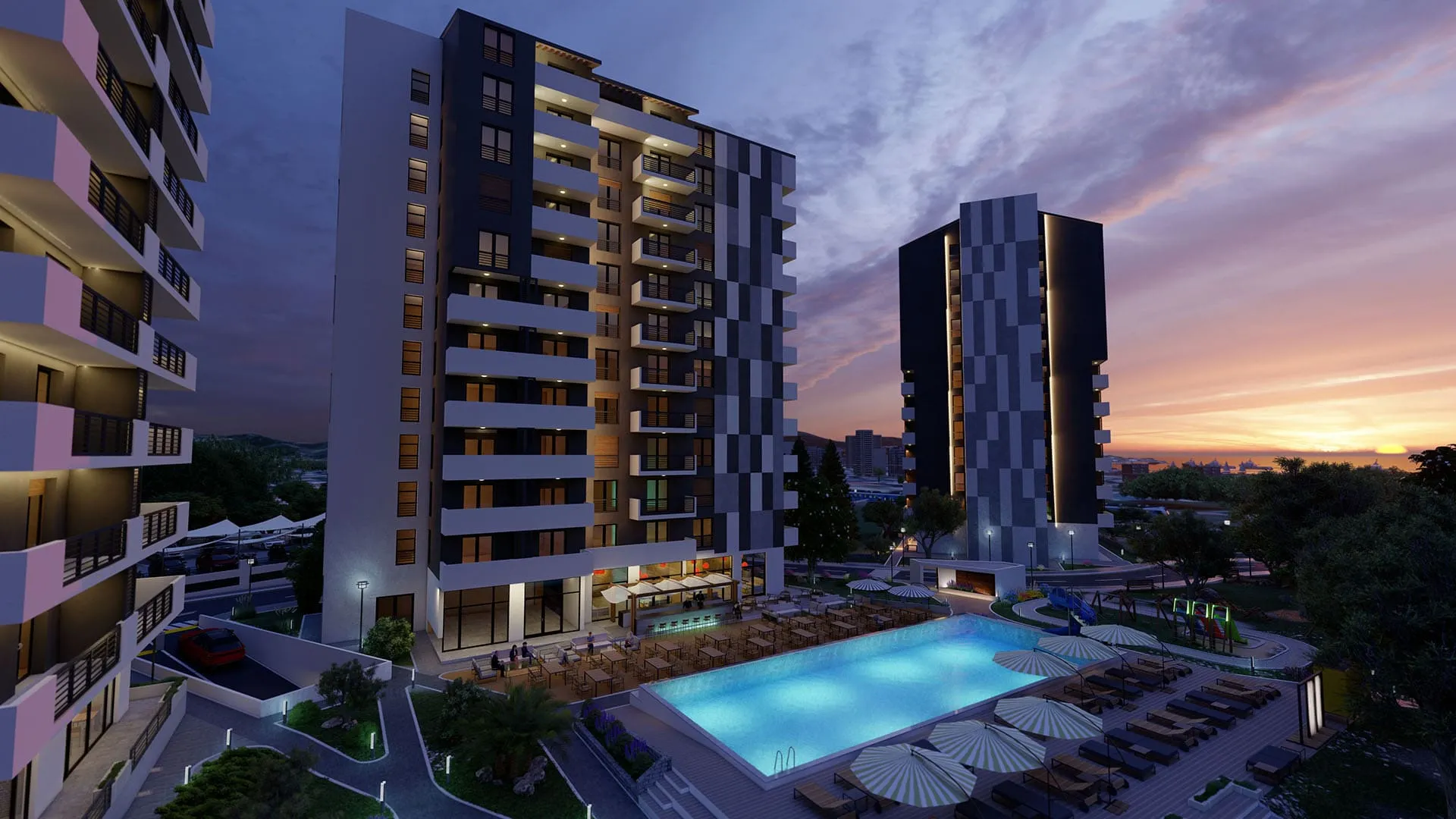 Exterior view of high-rise apartment buildings with an illuminated pool and terrace at sunset.