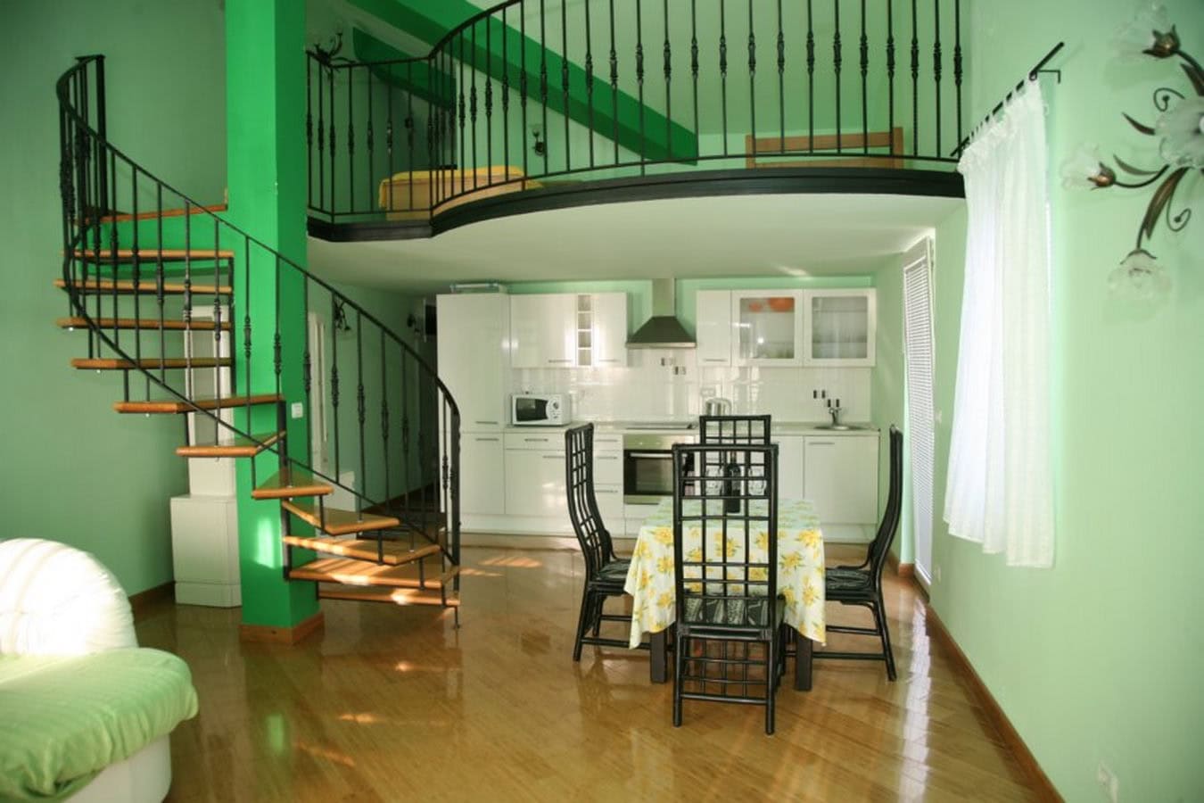 Living room with a spiral staircase and kitchen in a villa in Tivat, Montenegro: modern interior with a mezzanine and dining area.