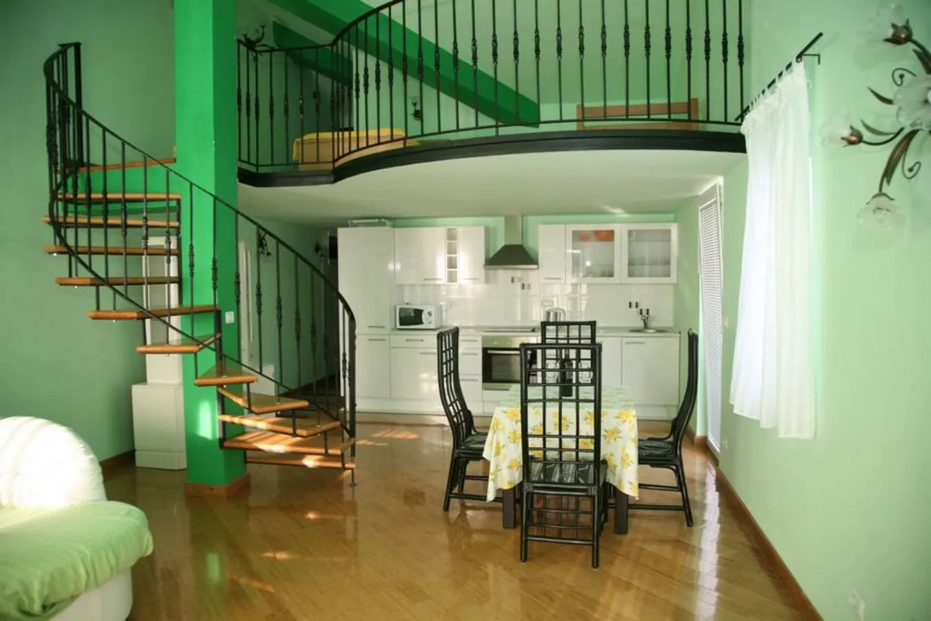 Living room with kitchen, spiral staircase, and dining area on light parquet.