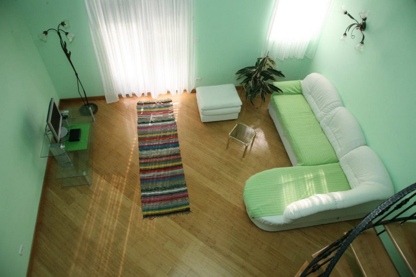 Bright living room with green walls, a white sofa, and wooden flooring in a villa in Tivat, Montenegro.
