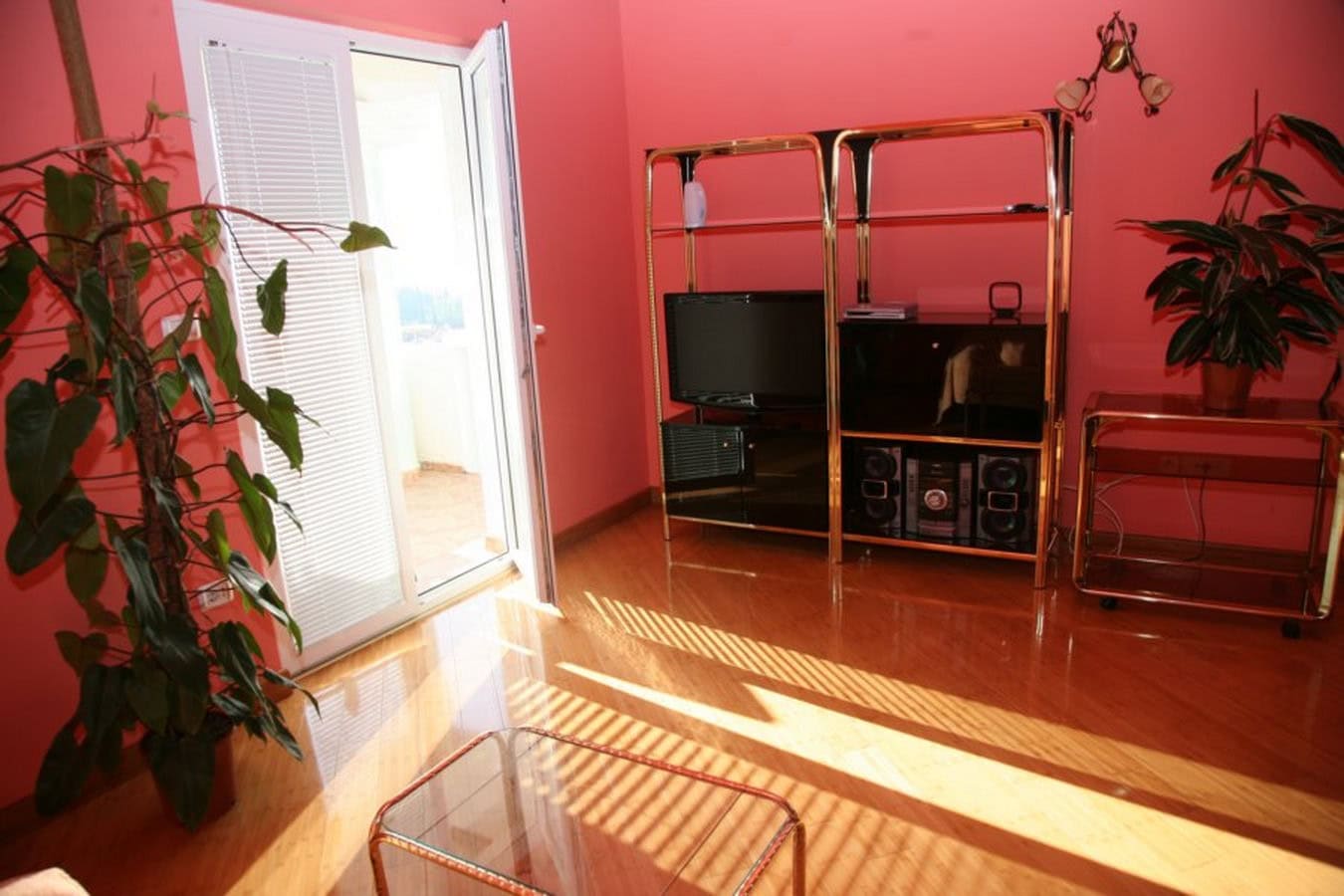 Living room with pink walls, retro-style furniture, and access to the terrace in a villa in Tivat, Montenegro.