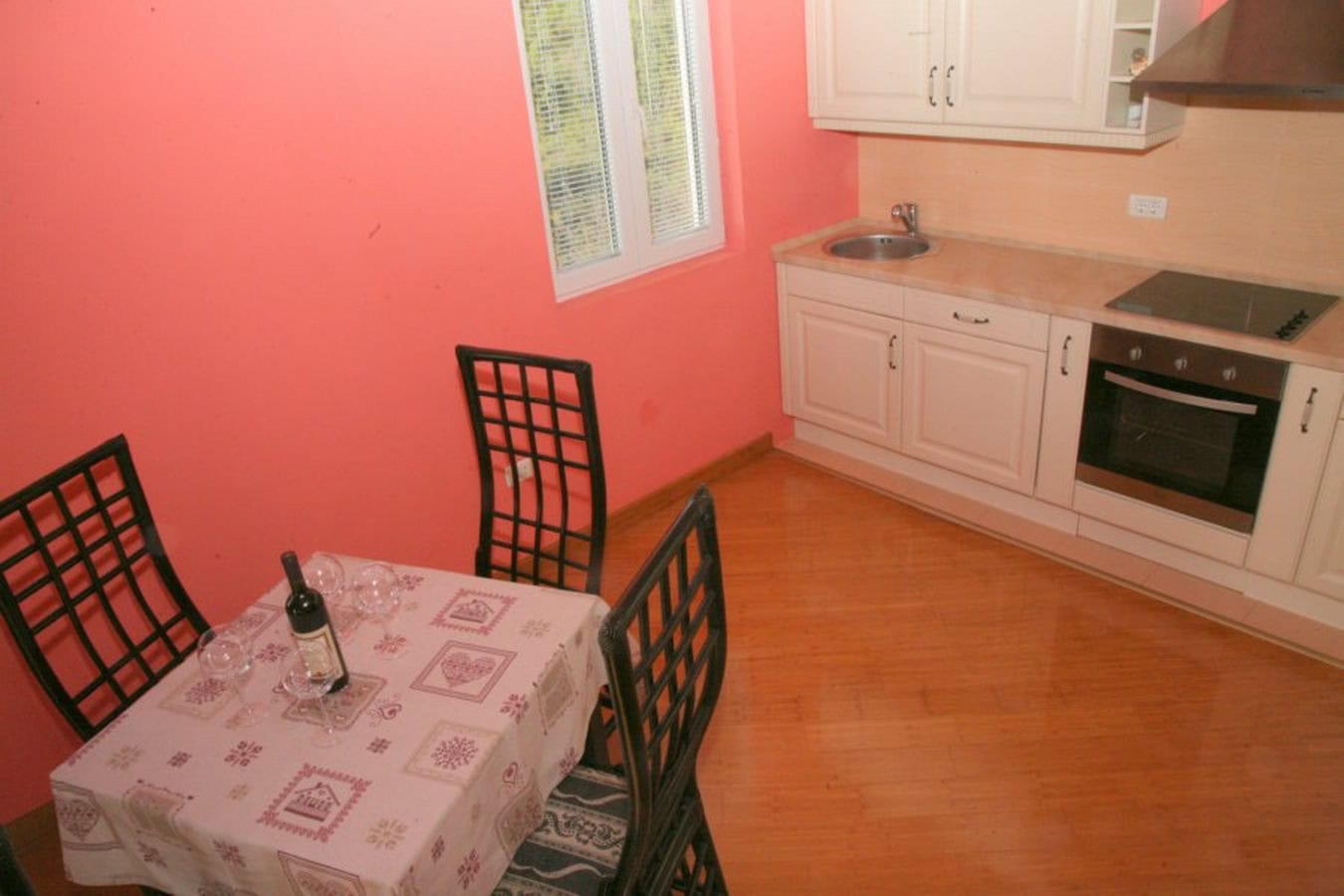 Kitchen with white cabinetry and dining area in a villa in Tivat, Montenegro: light furniture, built-in appliances.