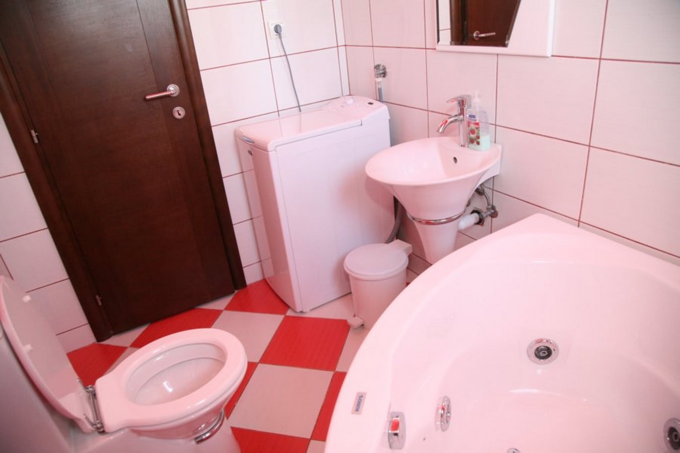 Bathroom with a jacuzzi and washing machine in a villa in Tivat, Montenegro: light tiles and fixtures.