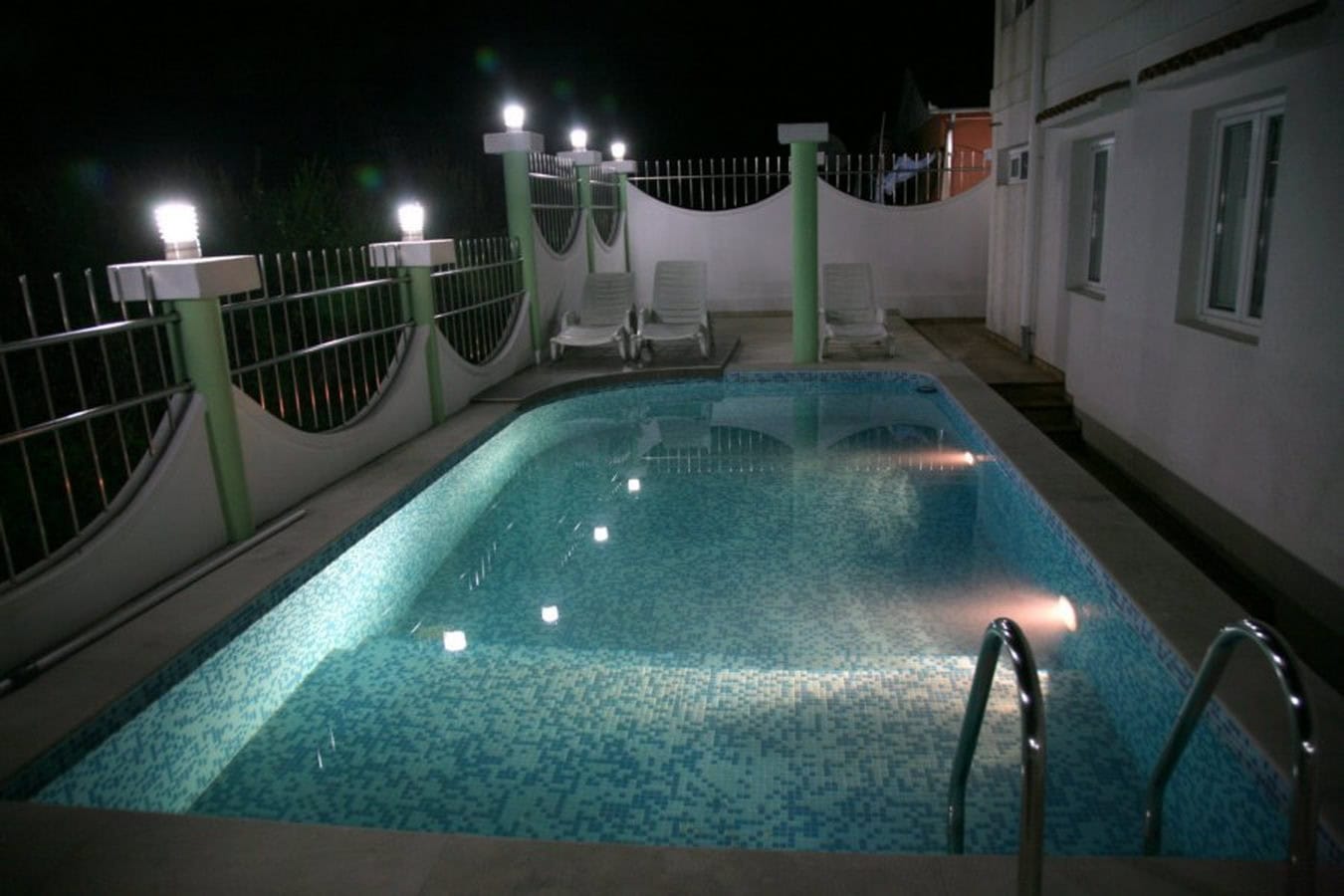 Private pool with lighting and sun loungers on the villa terrace in Tivat, Montenegro, in the evening.