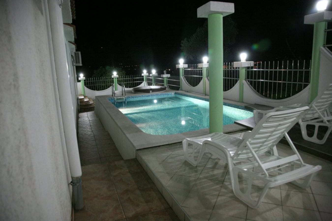 Outdoor pool with lighting and sun loungers on the villa terrace in Tivat, Montenegro, night view.