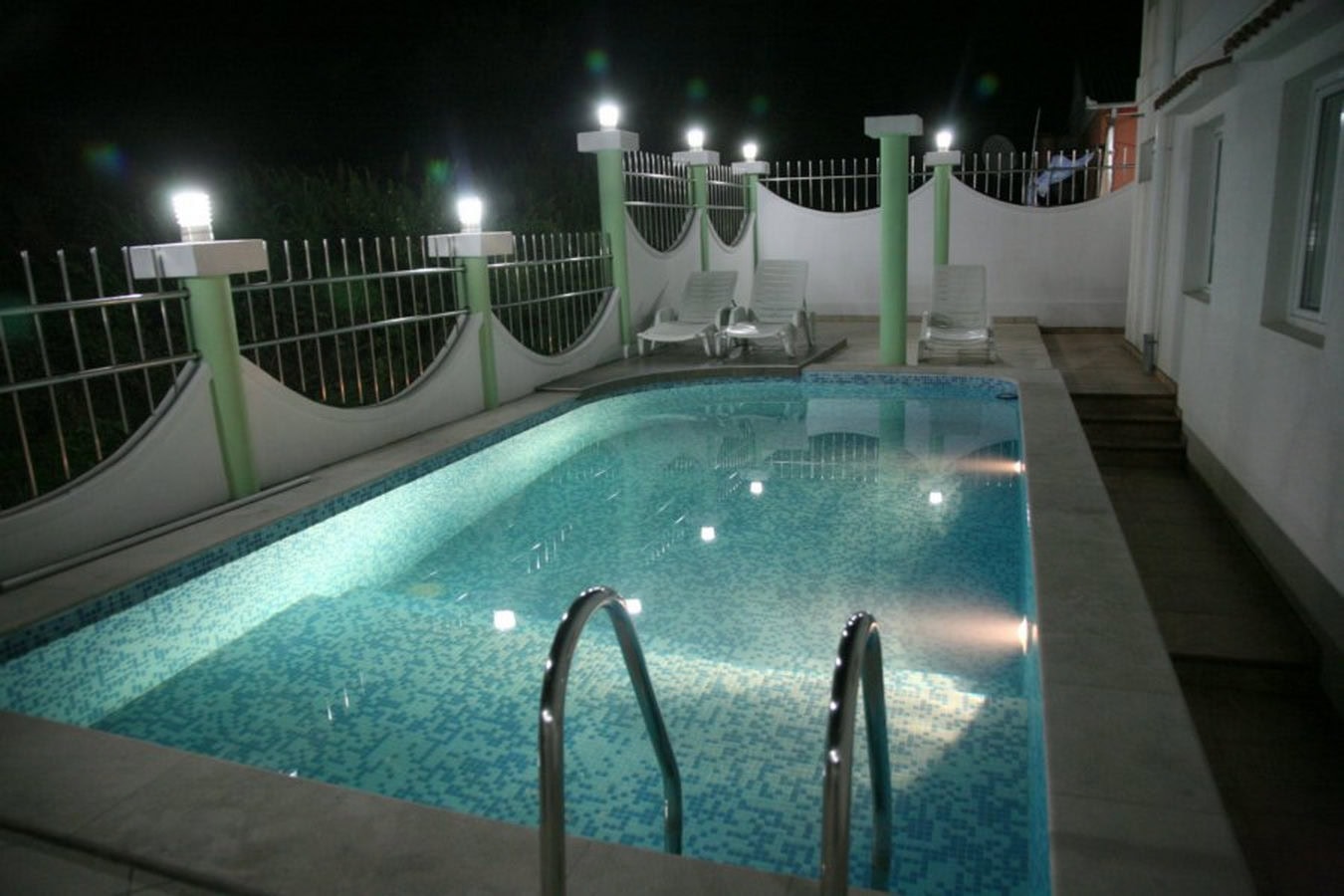 Private pool with lighting and sun loungers at a villa in Tivat, Montenegro, terrace view at night.