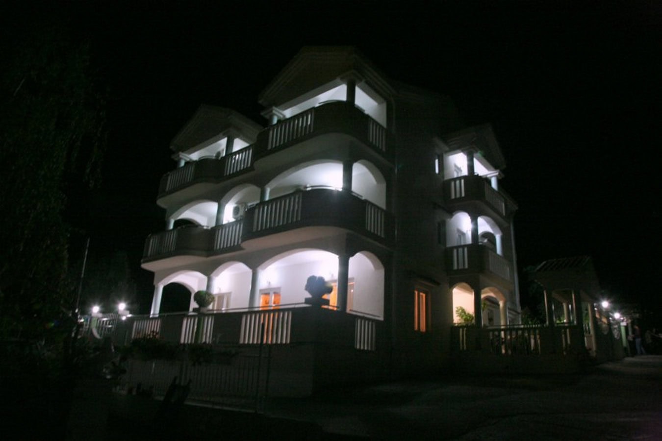 Three-story villa in Tivat, Montenegro, with night lighting, arched balconies, and a terrace in a classic style.