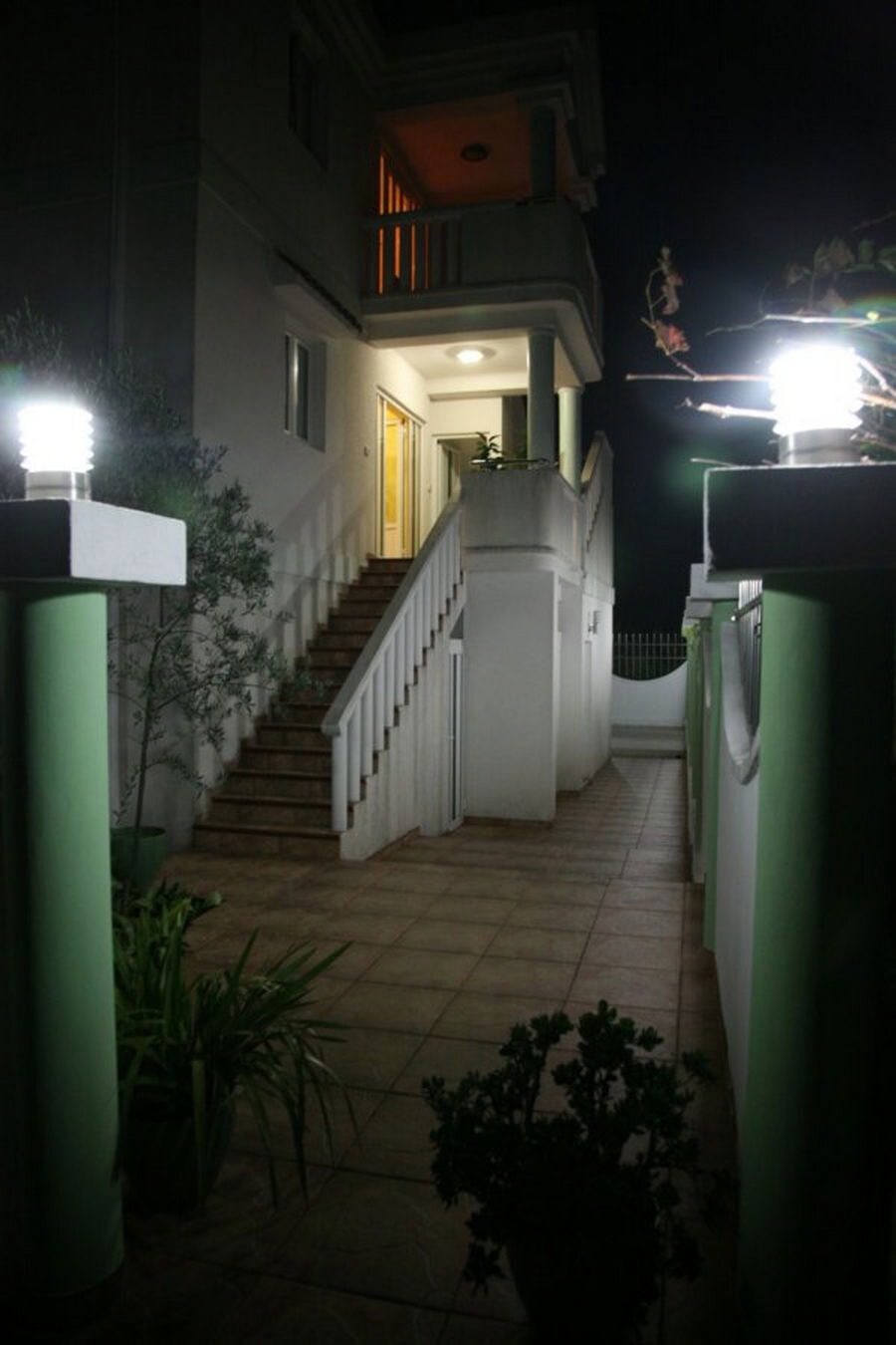 Night facade lighting of a villa in Tivat, Montenegro: stone staircase, terrace, and a well-kept courtyard with plants.