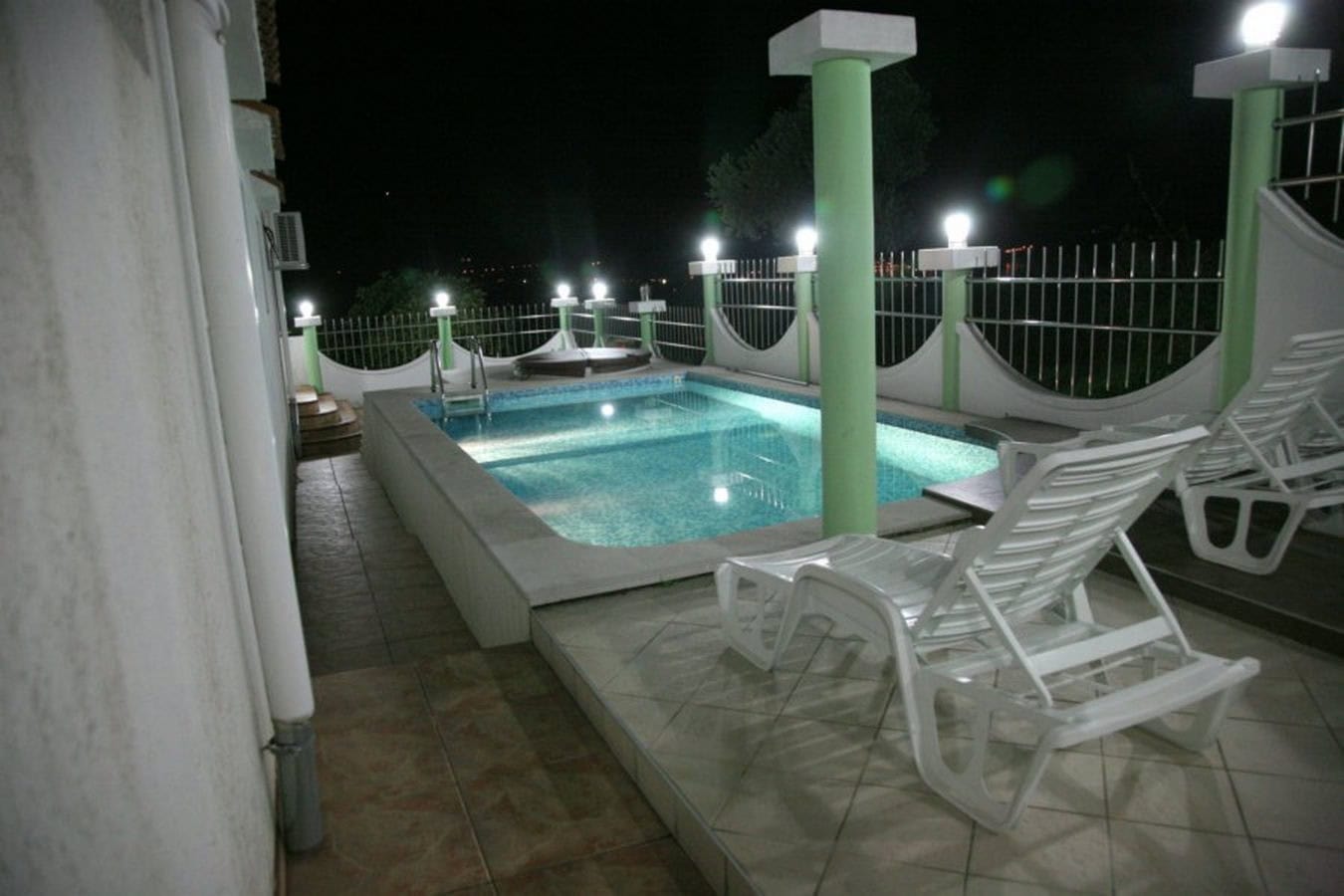Outdoor pool with lighting and sun loungers on the villa terrace in Tivat, Montenegro, night view.