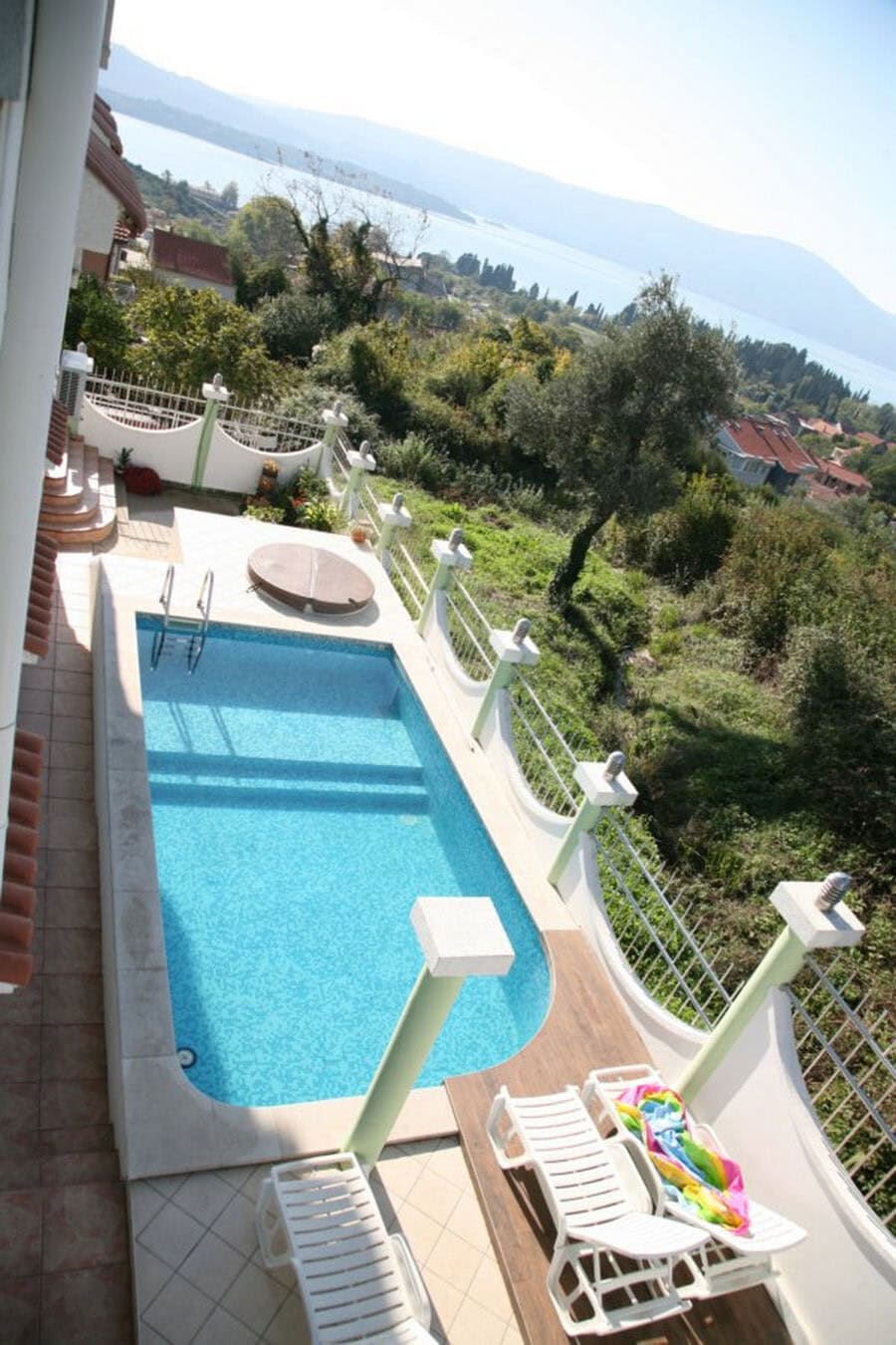 Outdoor pool with sea and mountain views at a villa in Tivat, Montenegro: terrace with sun loungers and landscaped design.