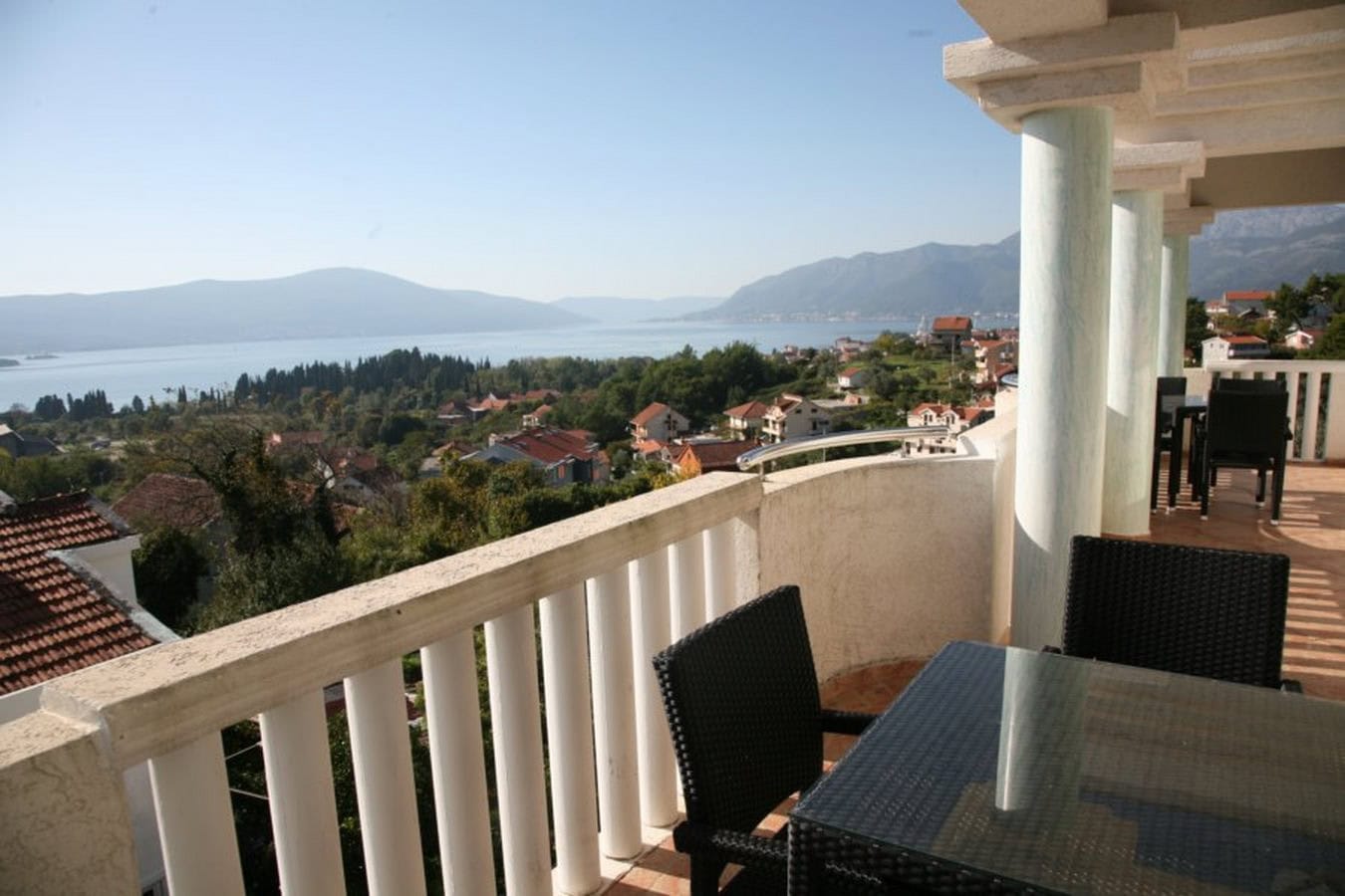 Spacious villa terrace in Tivat, Montenegro, with panoramic sea and mountain views and wicker furniture for relaxing.