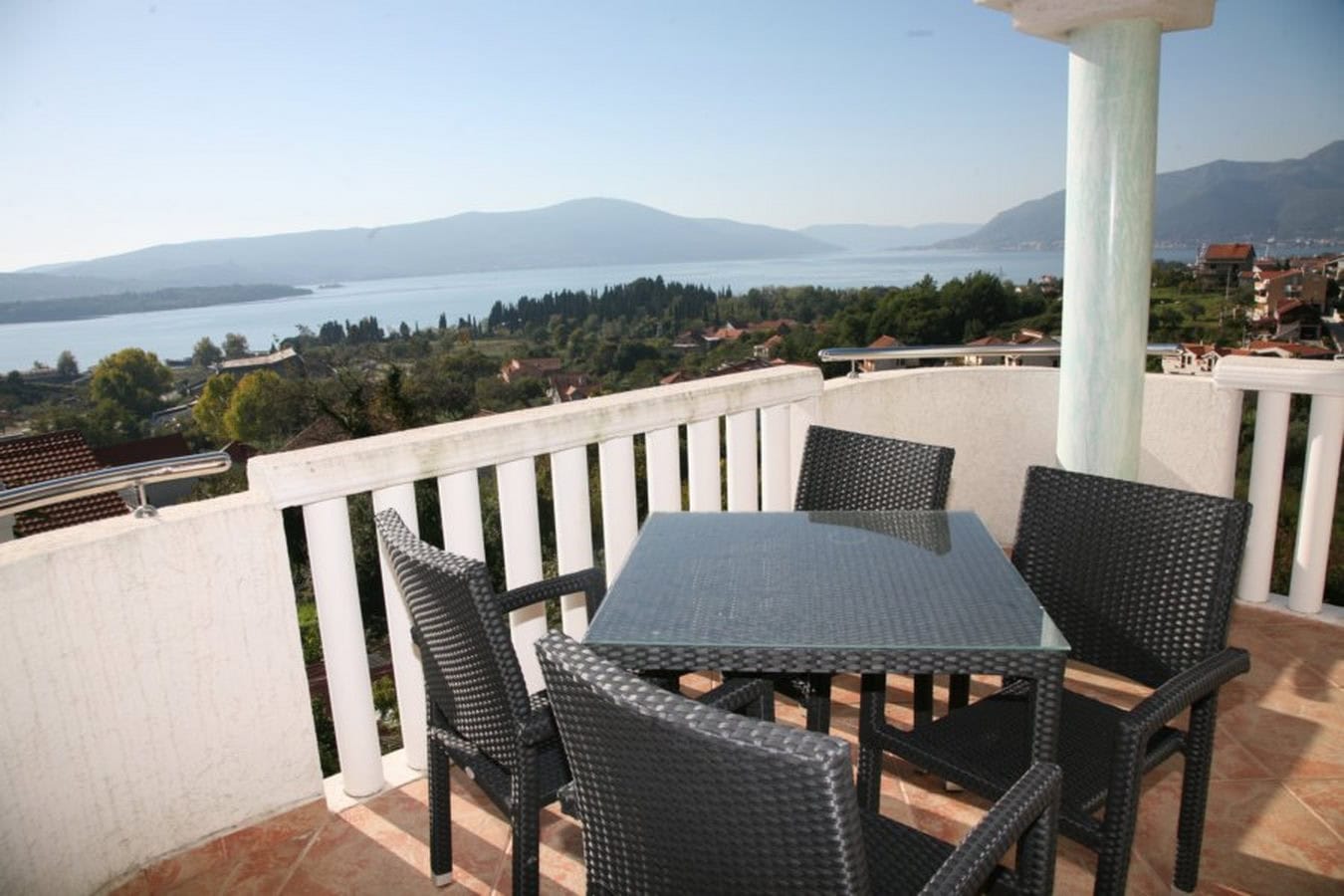 Terrace with wicker furniture and panoramic views of the sea and mountains in a villa in Tivat, Montenegro.