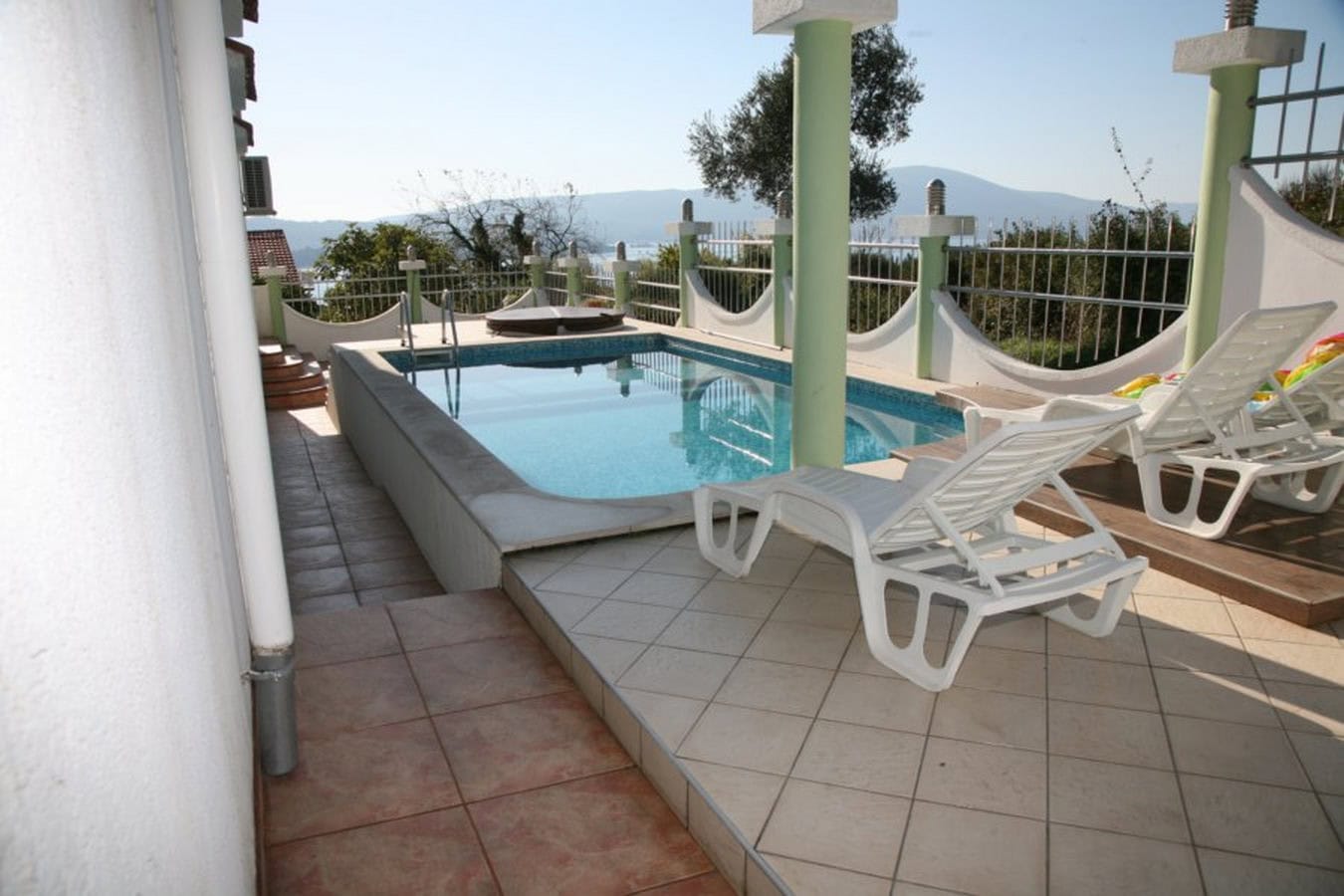 Open terrace with a pool and sun loungers at a villa in Tivat, Montenegro, with panoramic sea and mountain views.