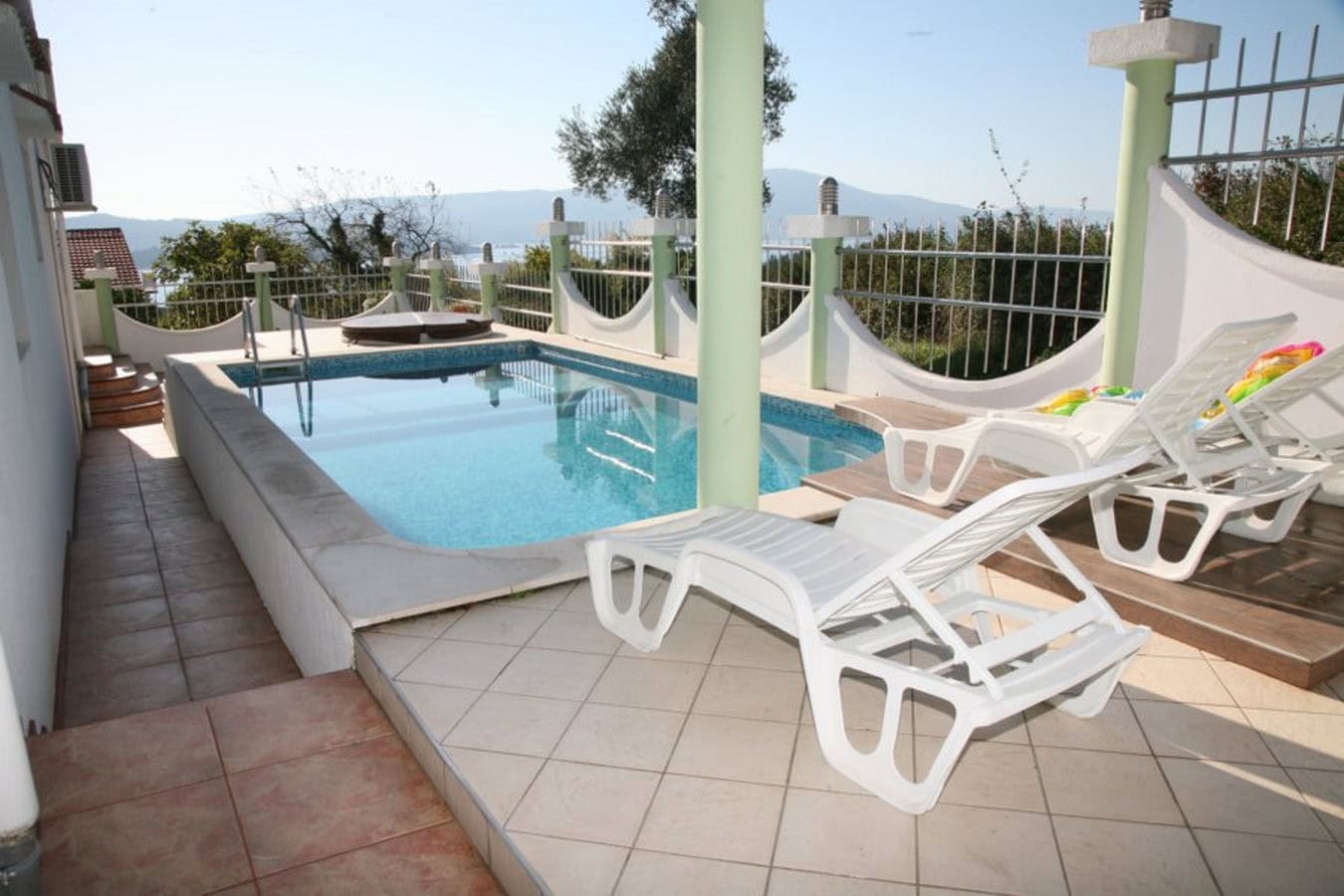 Pool with sun loungers on the villa terrace in Tivat, Montenegro, with panoramic sea and mountain views.