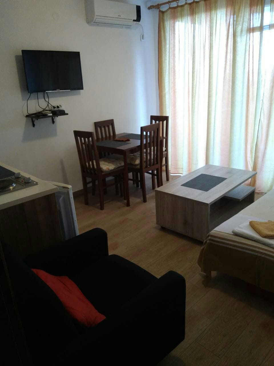 Living room in a house in Shushan, Montenegro: dining area, wooden table, TV, air conditioner, and an armchair.