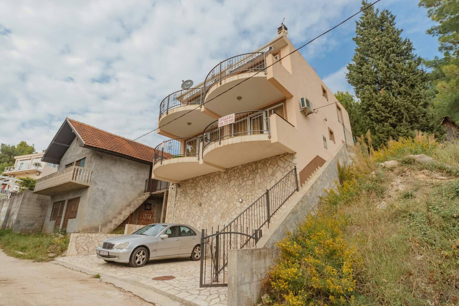 Three-story house with balconies and stone facade cladding for sale in Shushan, Montenegro, with parking at the entrance.