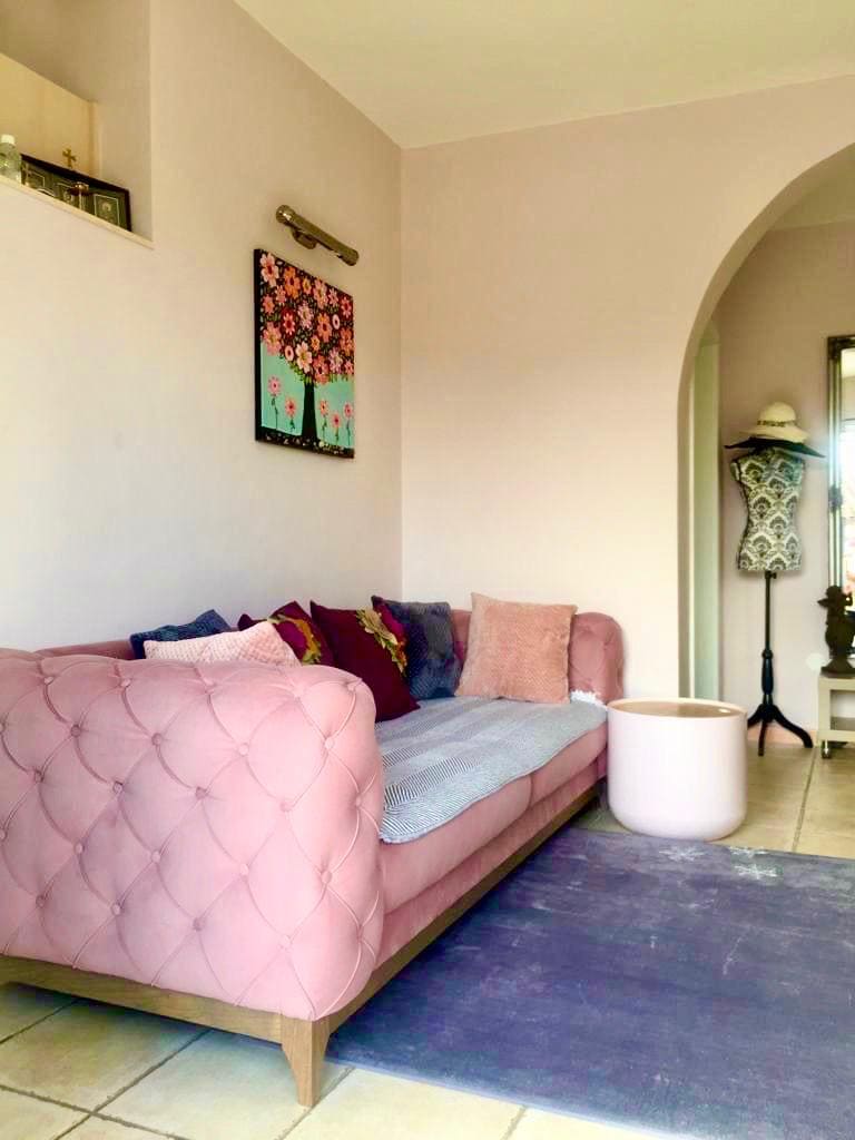 Living room with a pink sofa in a villa interior in Shushan, Montenegro: a cozy seating area with an arched passage.