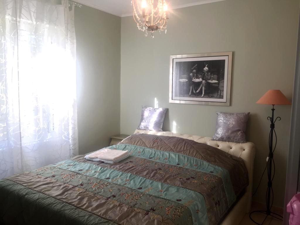 Cozy bedroom with a double bed in a villa, Shushan, Montenegro: light walls, a classic chandelier, and a floor lamp.