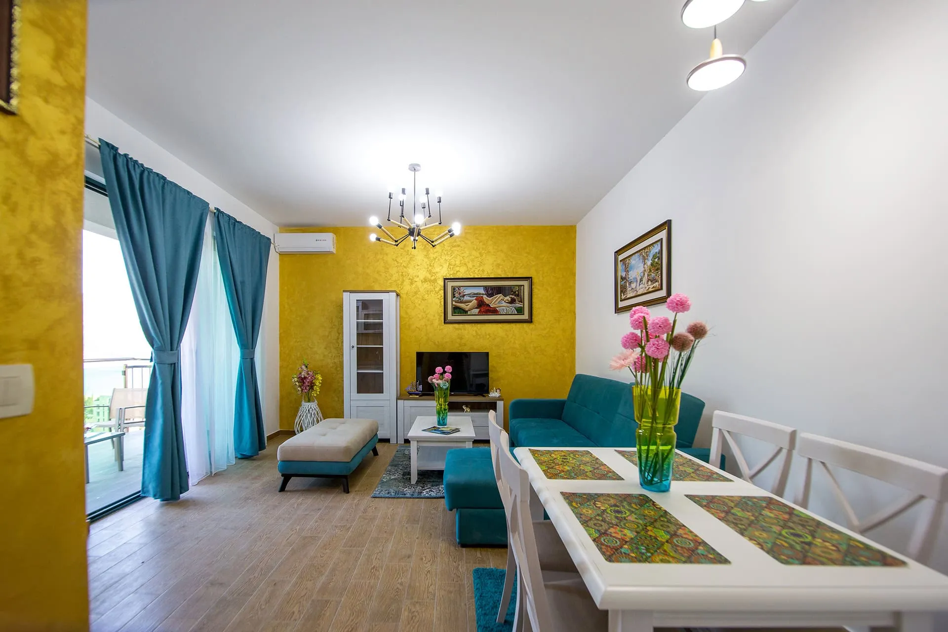 Living room with yellow wall, blue sofa, white dining table, and TV.