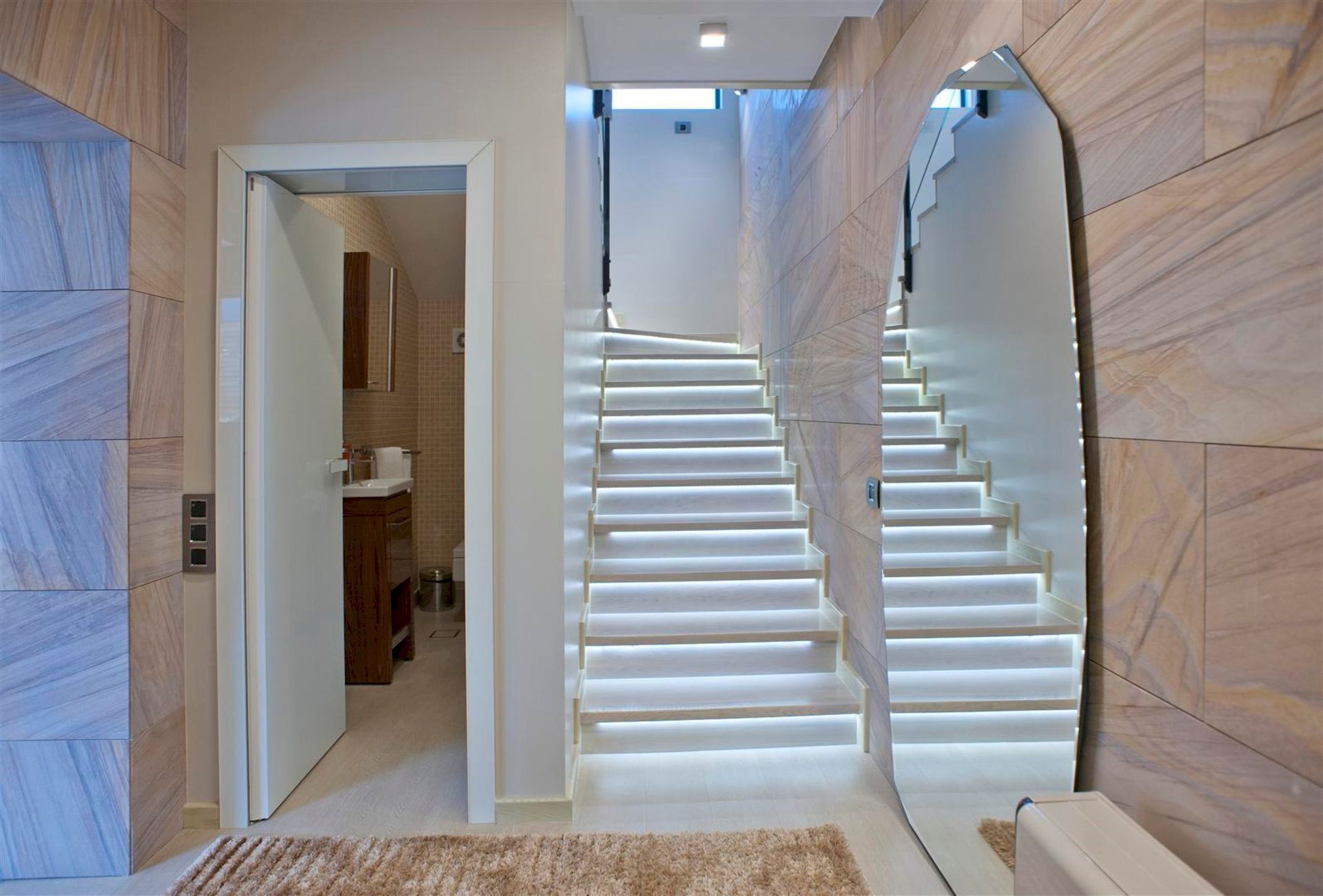 Staircase with lighting and a mirror in a modern villa interior in Krašići, Montenegro, with access to the bathroom.