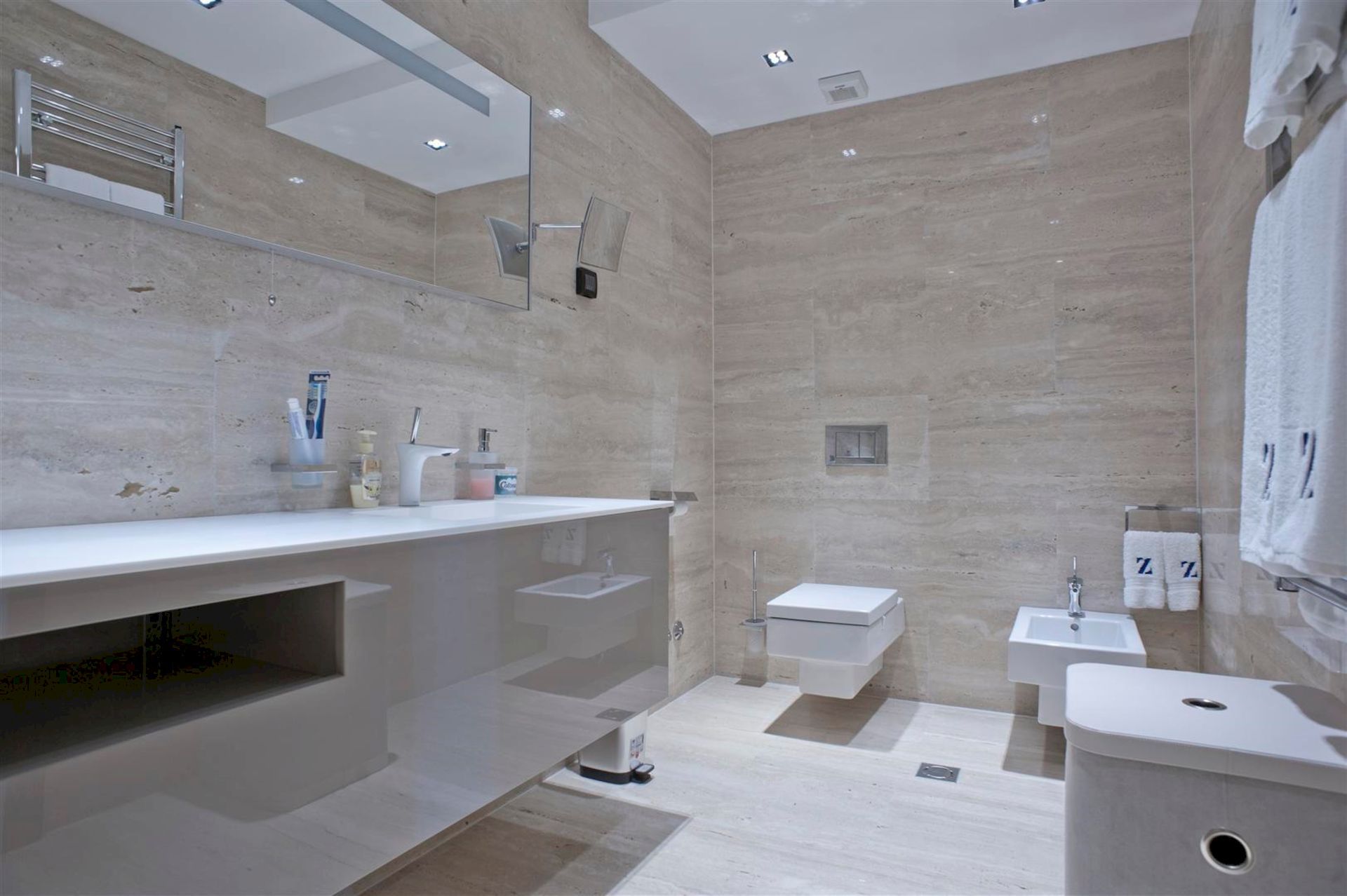Modern bathroom with beige stone finishes, wall-mounted fixtures, and a mirror in a villa in Krašići, Montenegro
