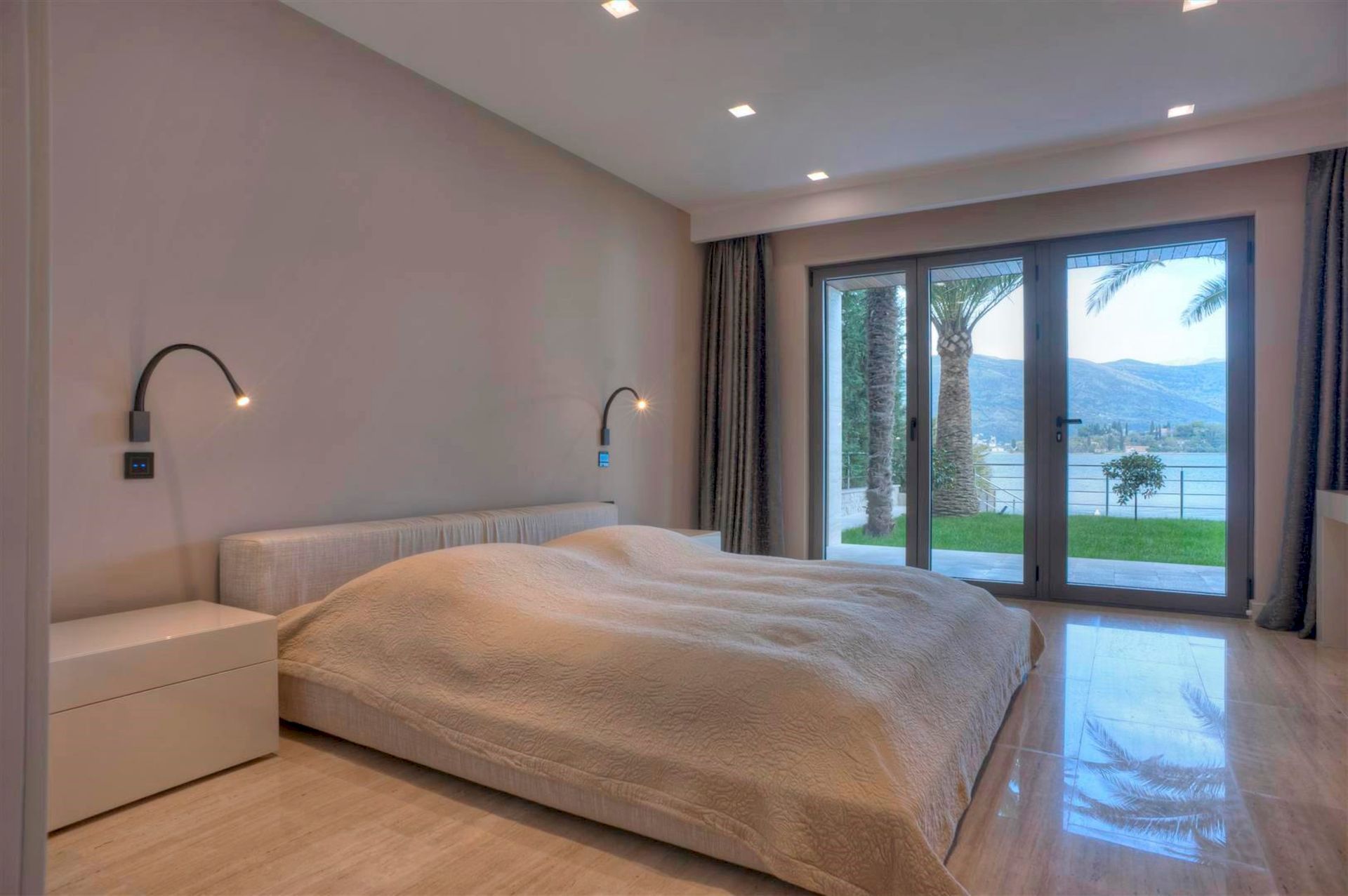 Modern bedroom in a villa in Krašići, Montenegro, with a double bed and panoramic sea and mountain views.