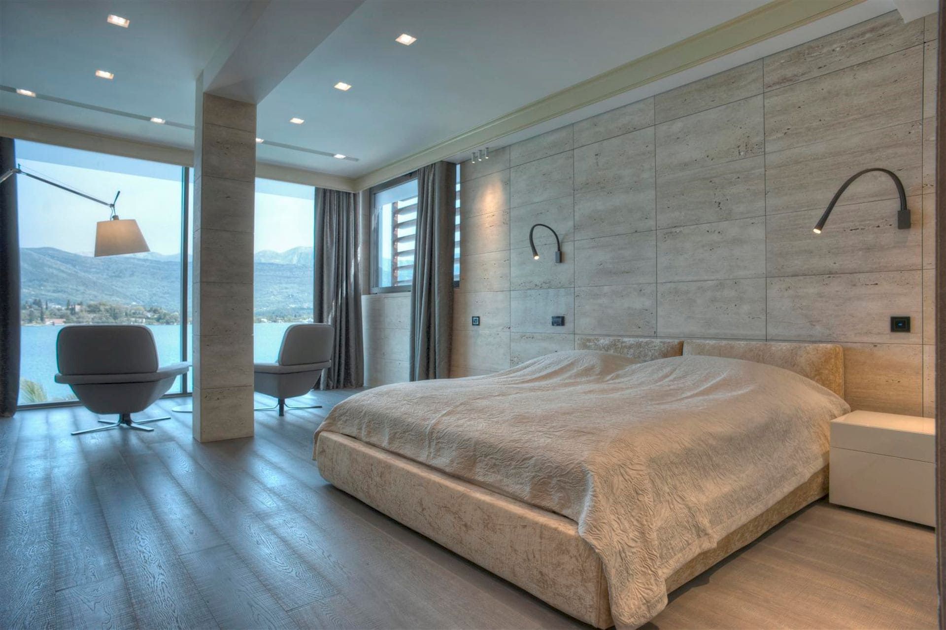 Modern bedroom with panoramic sea and mountain views in a villa, Krašići, Montenegro: stone finishes and a double bed.