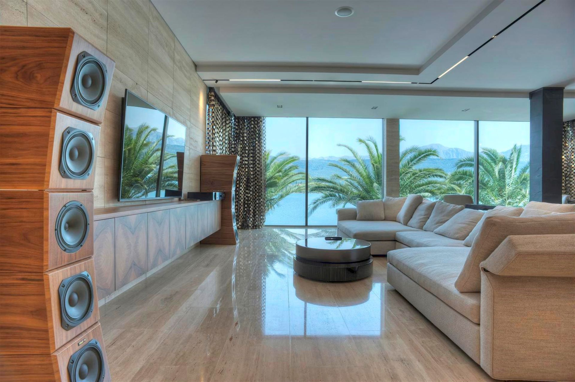 Living room of a luxury villa in Krašići, Montenegro: panoramic windows with sea views, designer furniture, and sound system.
