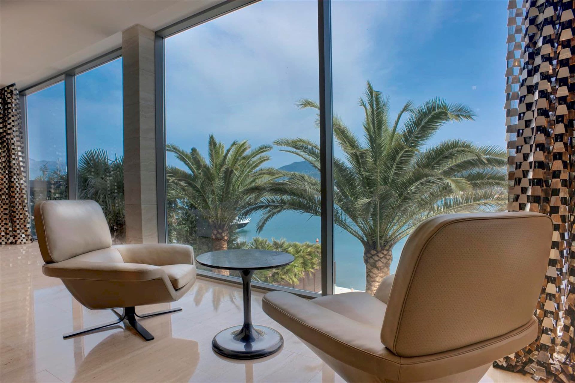 Living room with panoramic windows and sea and palm views in a luxury villa, Krašići, Montenegro.