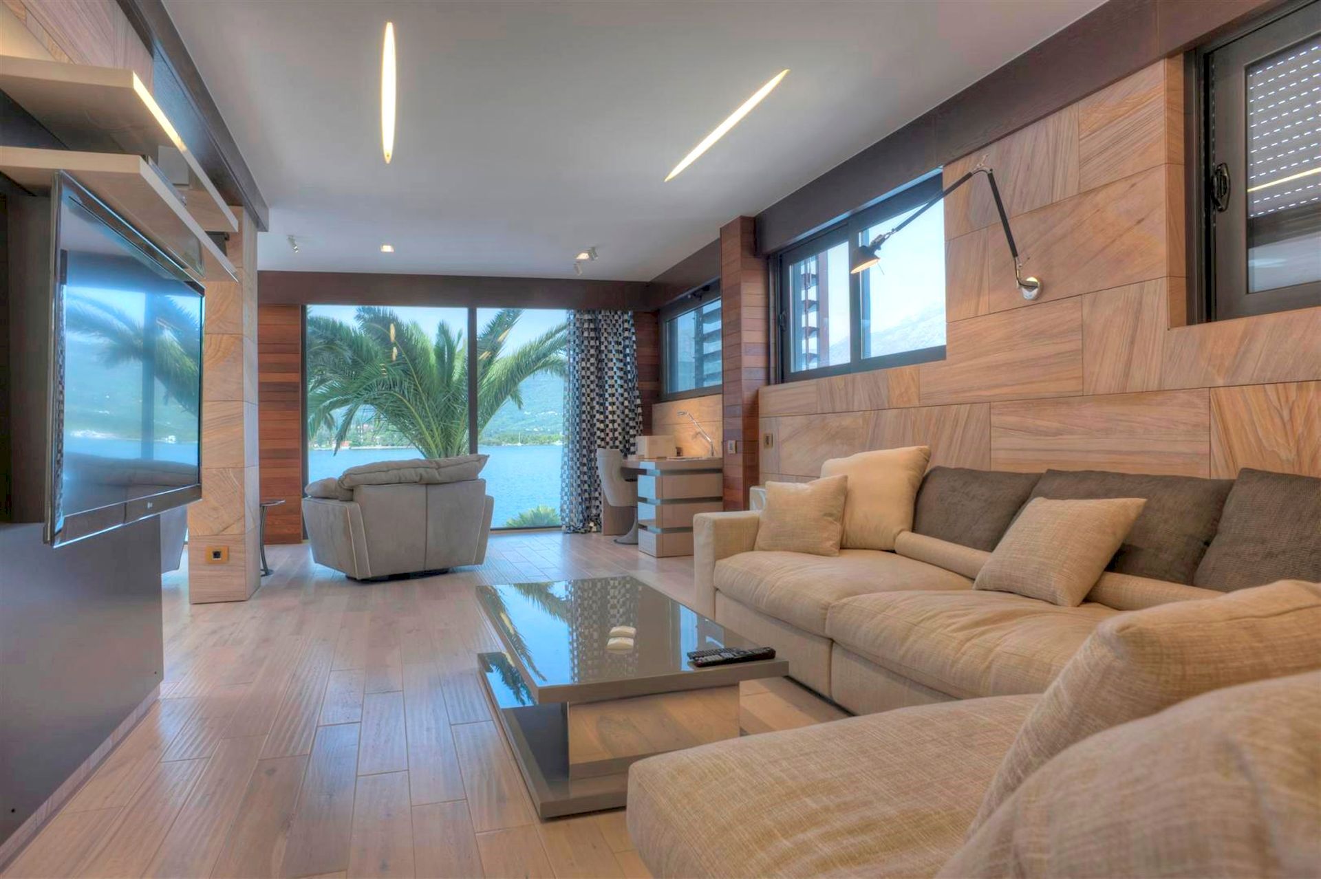 Modern living room in a villa in Krašići, Montenegro: panoramic sea view, wood finishes, and soft seating.