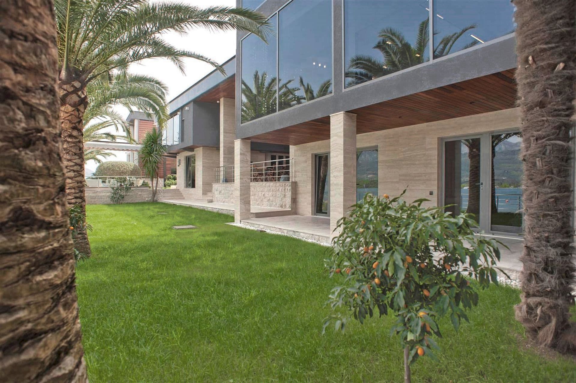 Modern villa with panoramic windows, a terrace, and a green garden in Krašići, Montenegro. Luxury seaside property.