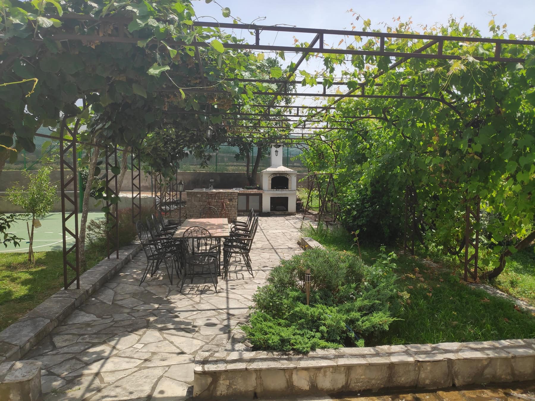 Barbecue area with a stone grill and garden furniture in the cozy garden of a house in Bar, Montenegro.