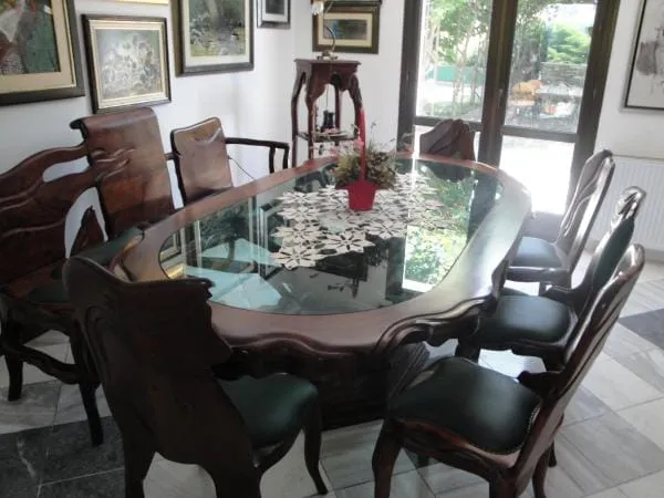 Dining area featuring a large wooden table with a glass top surrounded by ornate chairs.