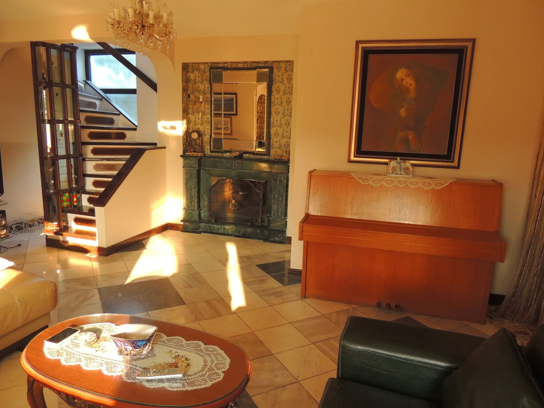 Living room in a house in Bar, Montenegro: a green stone fireplace, piano, staircase, and classic interior.