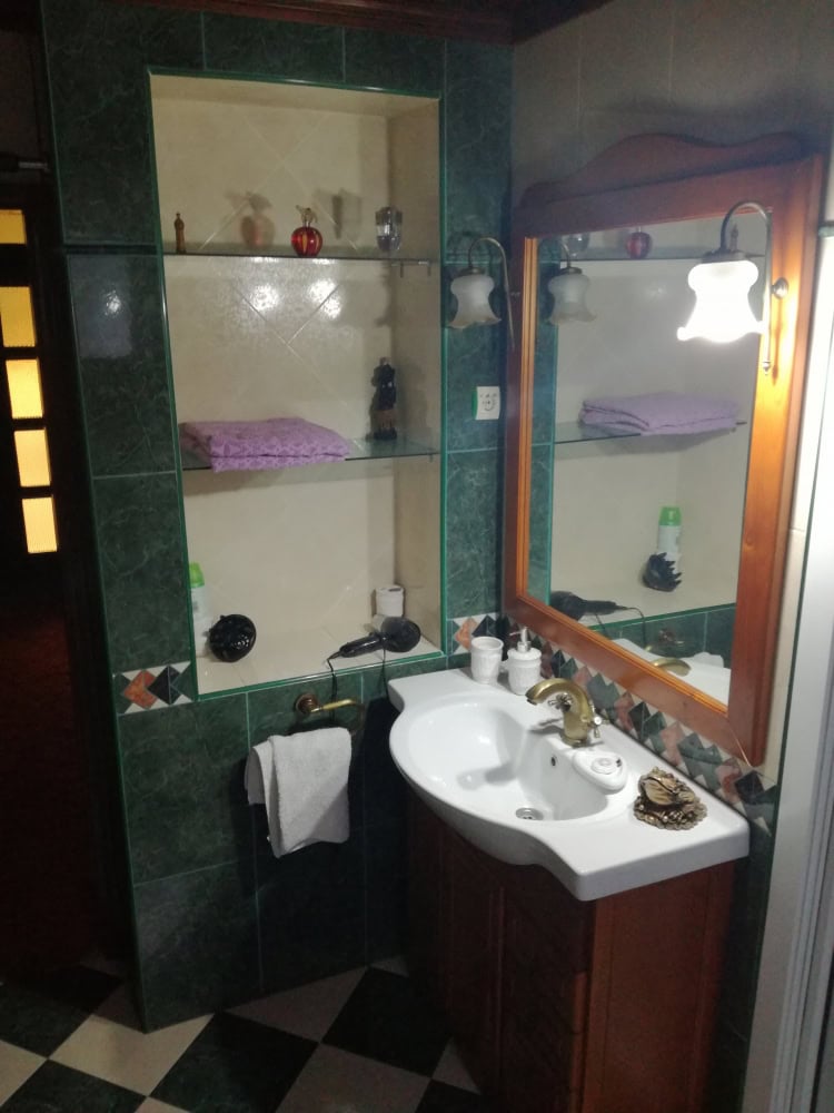 Bathroom in a house in Bar, Montenegro: sink with a wooden vanity, mirror, and built-in shelves with tile finish.