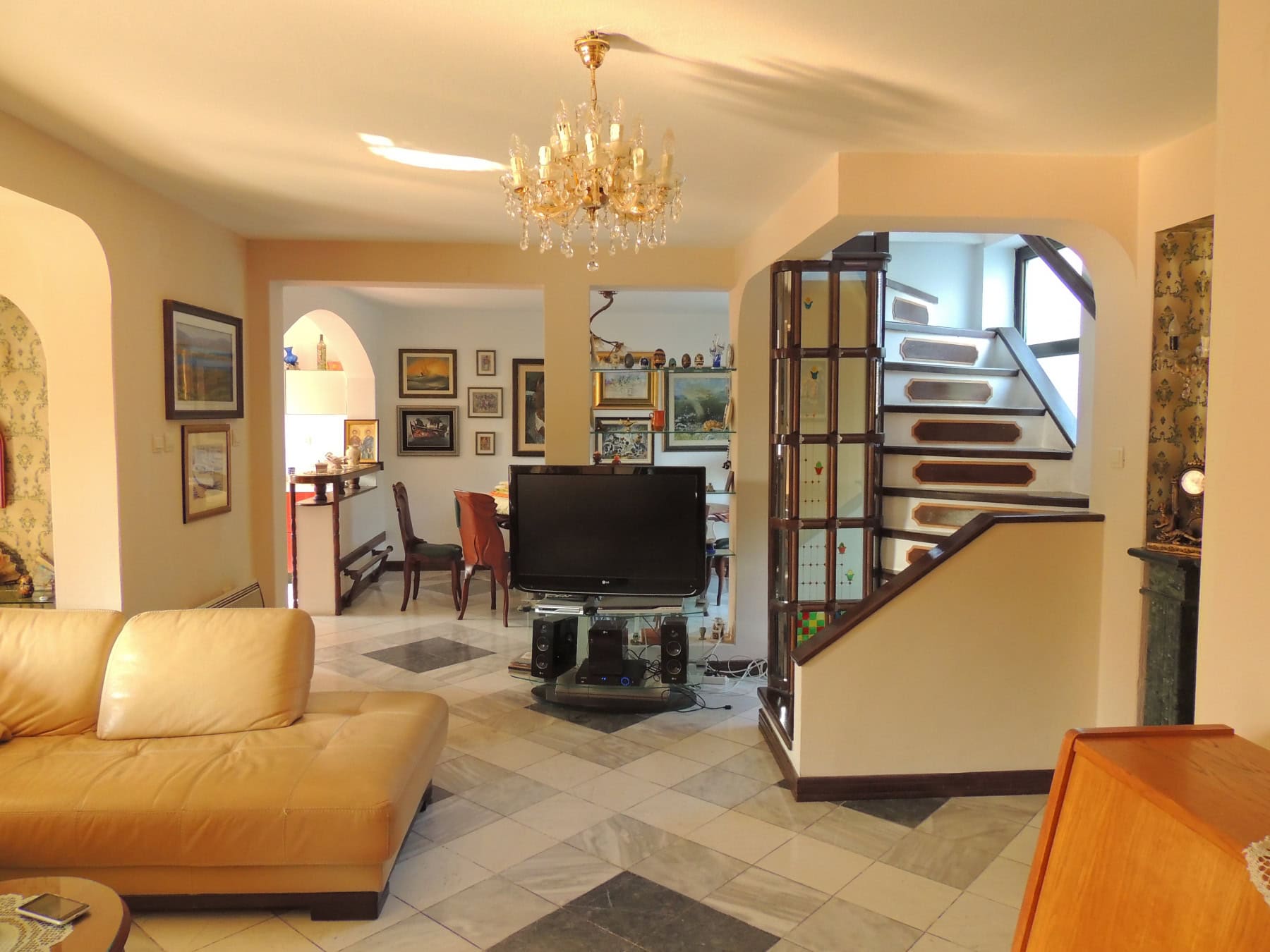 Spacious living room with a leather sofa and staircase in a house, Bar, Montenegro. Interior with marble flooring and decor.
