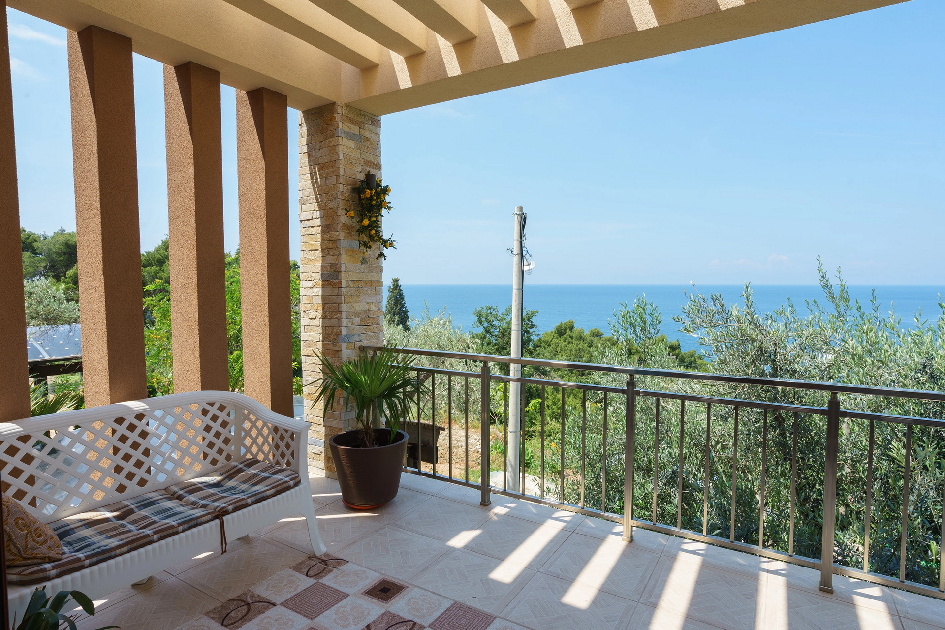 Terrace of a house in Sutomore, Montenegro: sea view, white garden furniture, stone finishes, and stainless steel railings.