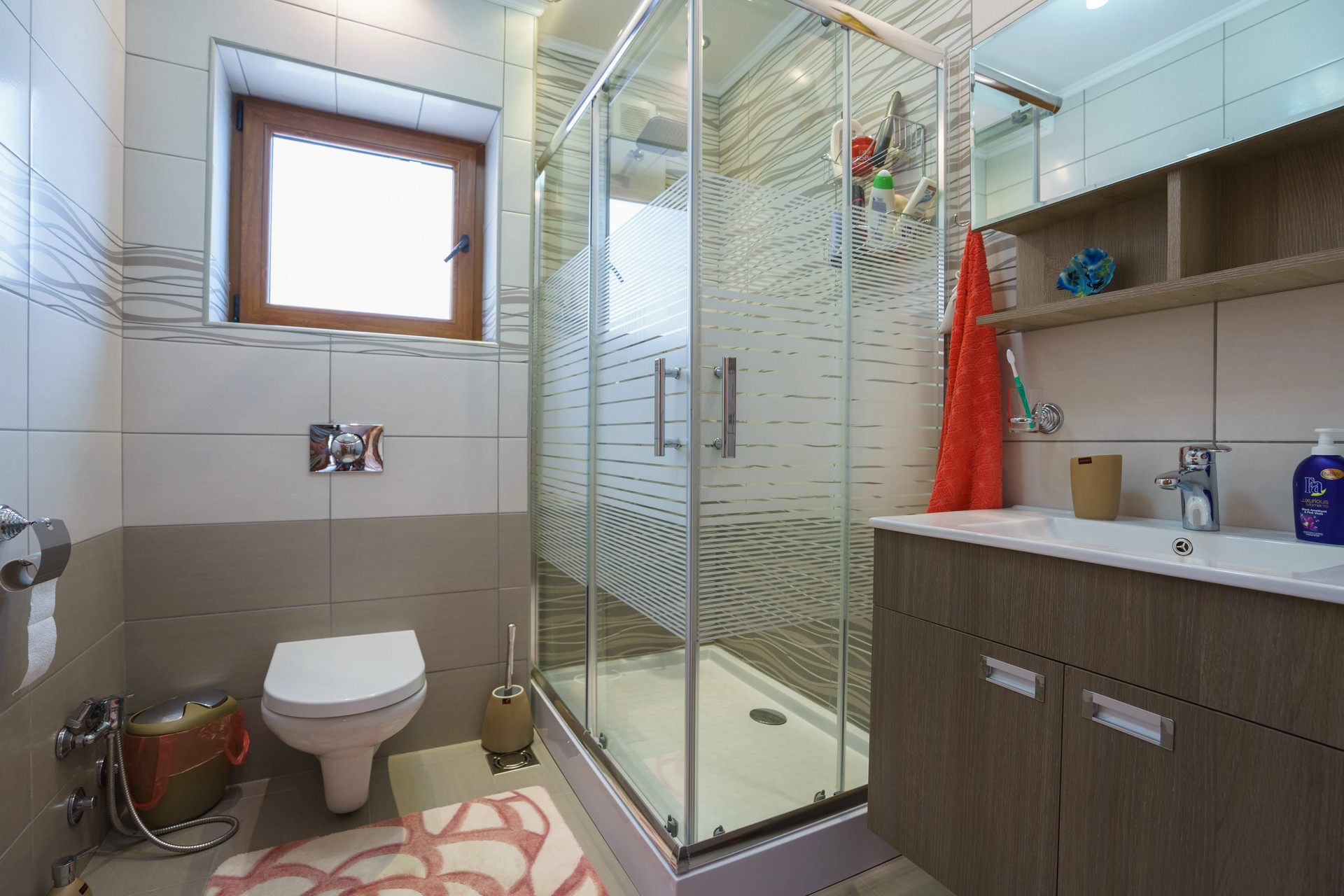 Modern bathroom with a shower cabin in a house, Sutomore, Montenegro: tile, vanity with sink, and window.
