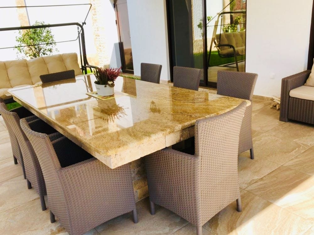 House terrace in Dobri Vody, Montenegro: outdoor dining area with a stone table and wicker furniture.